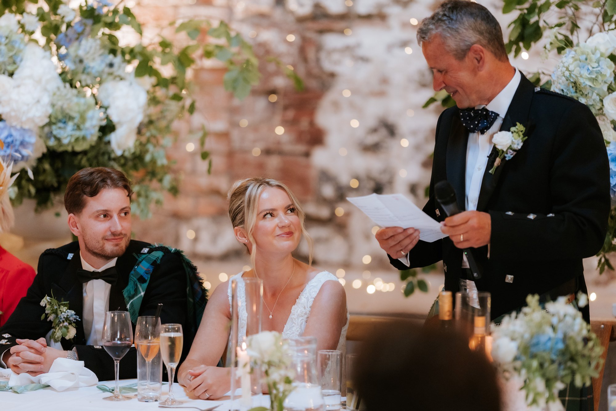 Lilian and Luke listening as her dad gives his wedding speech.