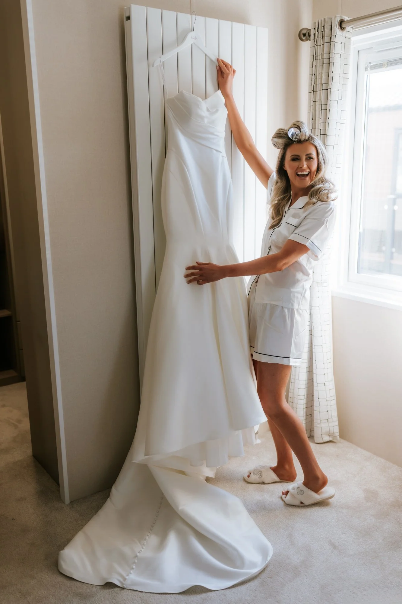 Natalie laughing beside her hanging wedding dress