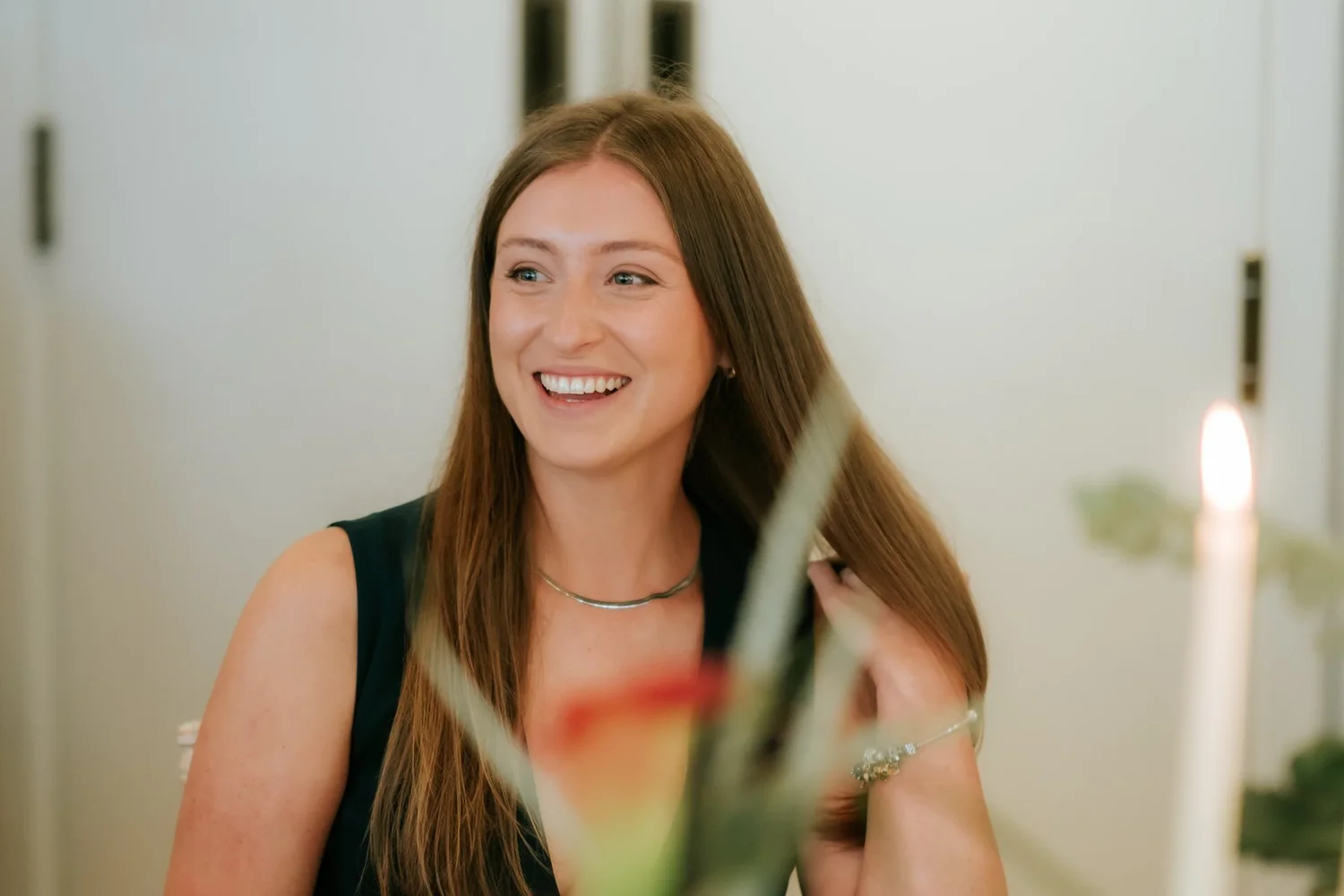 A guest in a green dress smiling across the table during the wedding breakfast.