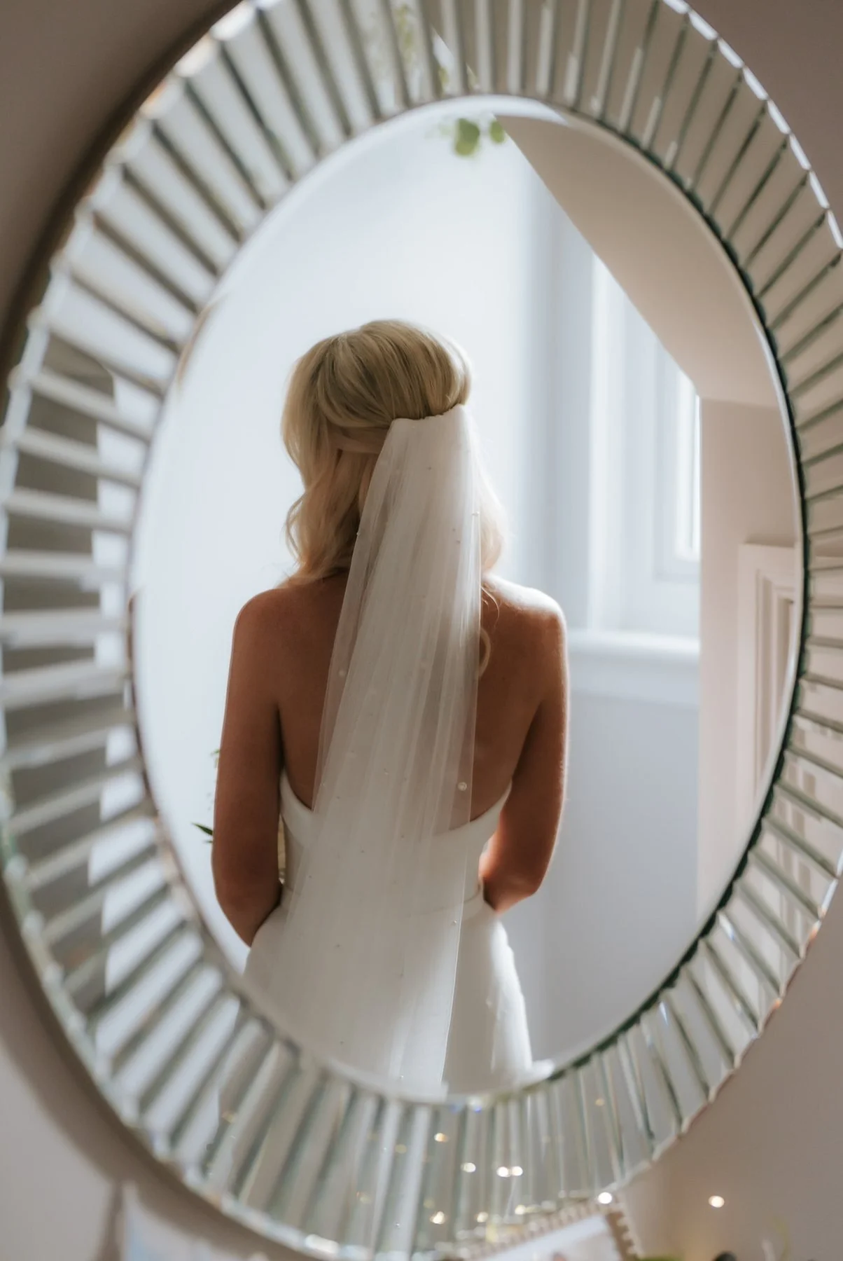 Lauren’s veil and Suzanne Neville dress reflected in a round mirror.
