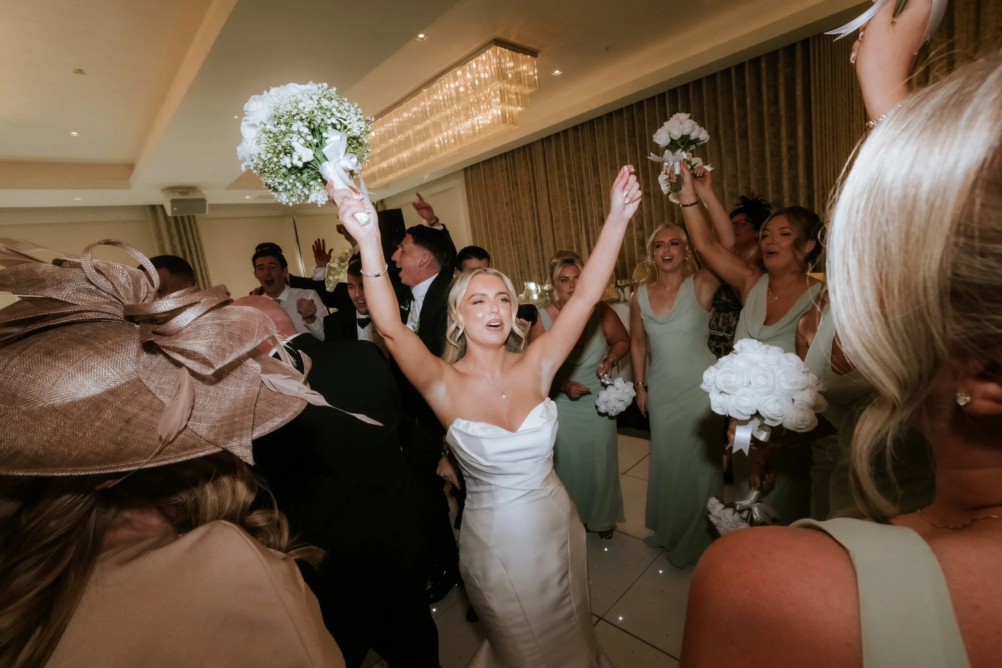 Taylor celebrating with her bouquet as guests cheer at the reception.