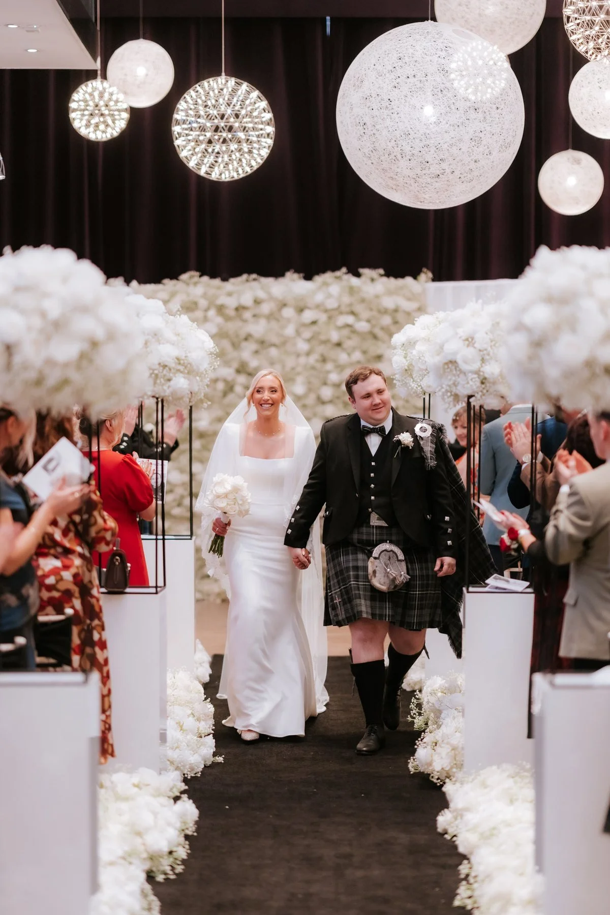 Jen and Jordan walking back up the aisle through their cheering guests.