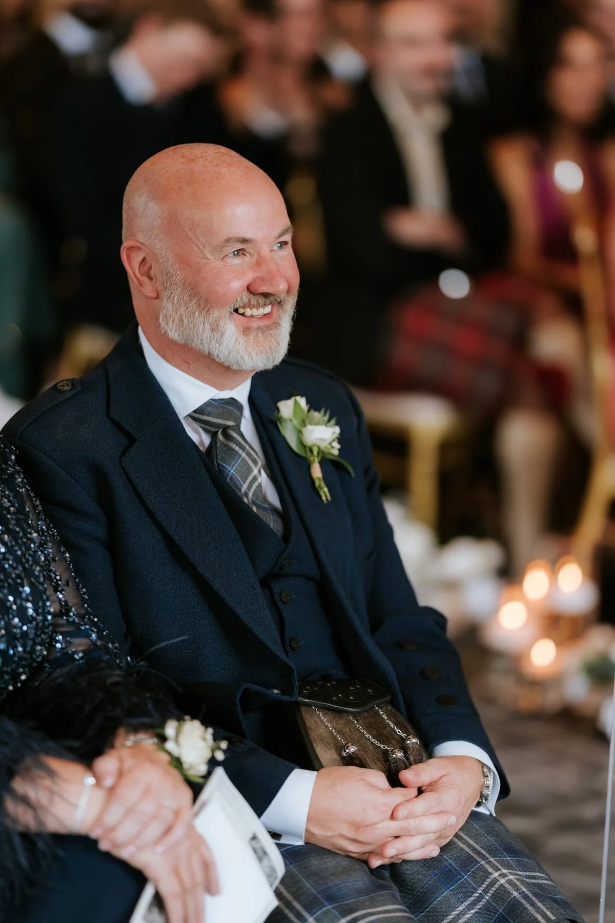 A smiling wedding guest in a navy suit watching Lauren and Zen’s ceremony.