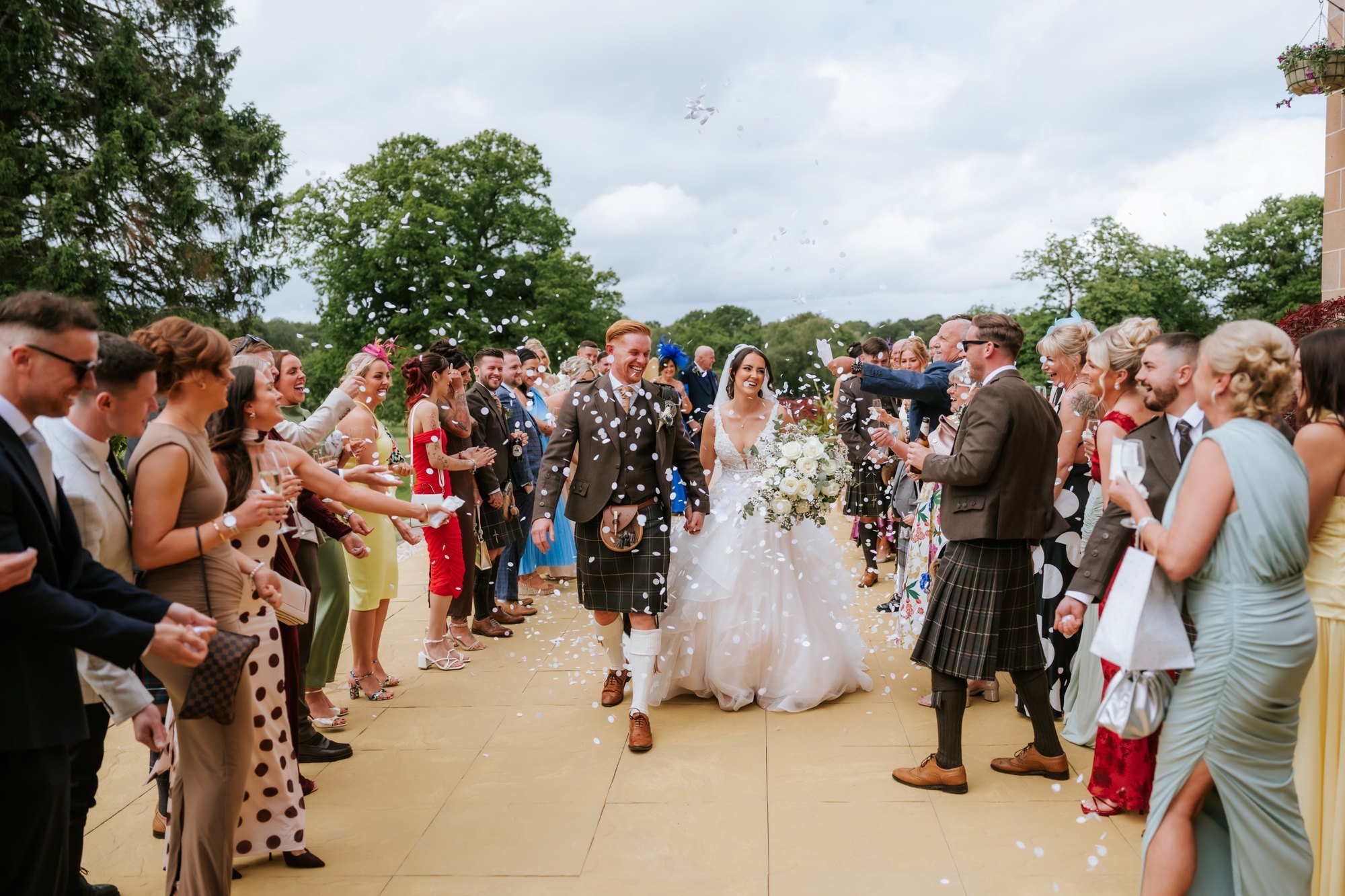 Kaitlyn and Scott walking through confetti thrown by their wedding guests at Glenbervie House.