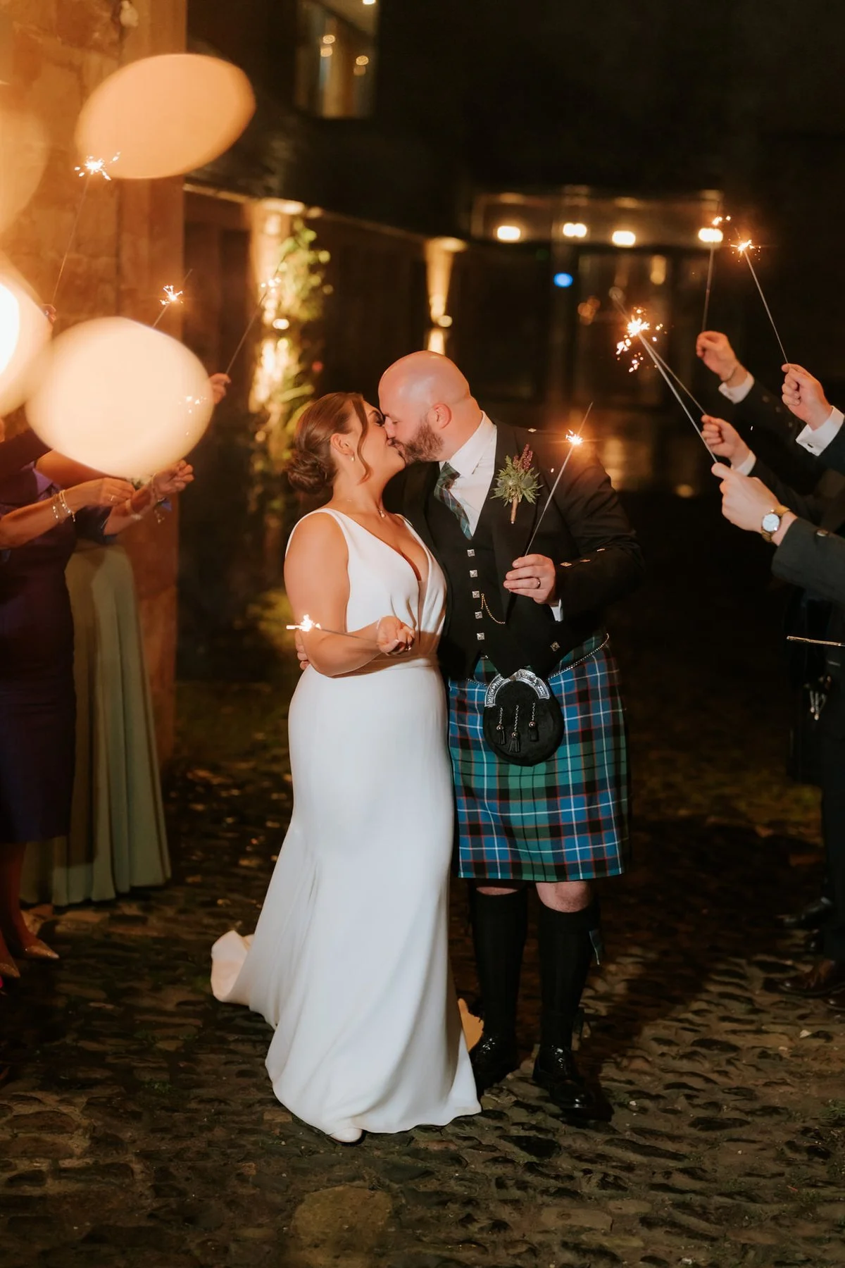 Kendall and Ewen kissing among the glowing sparklers at the end of their wedding day.