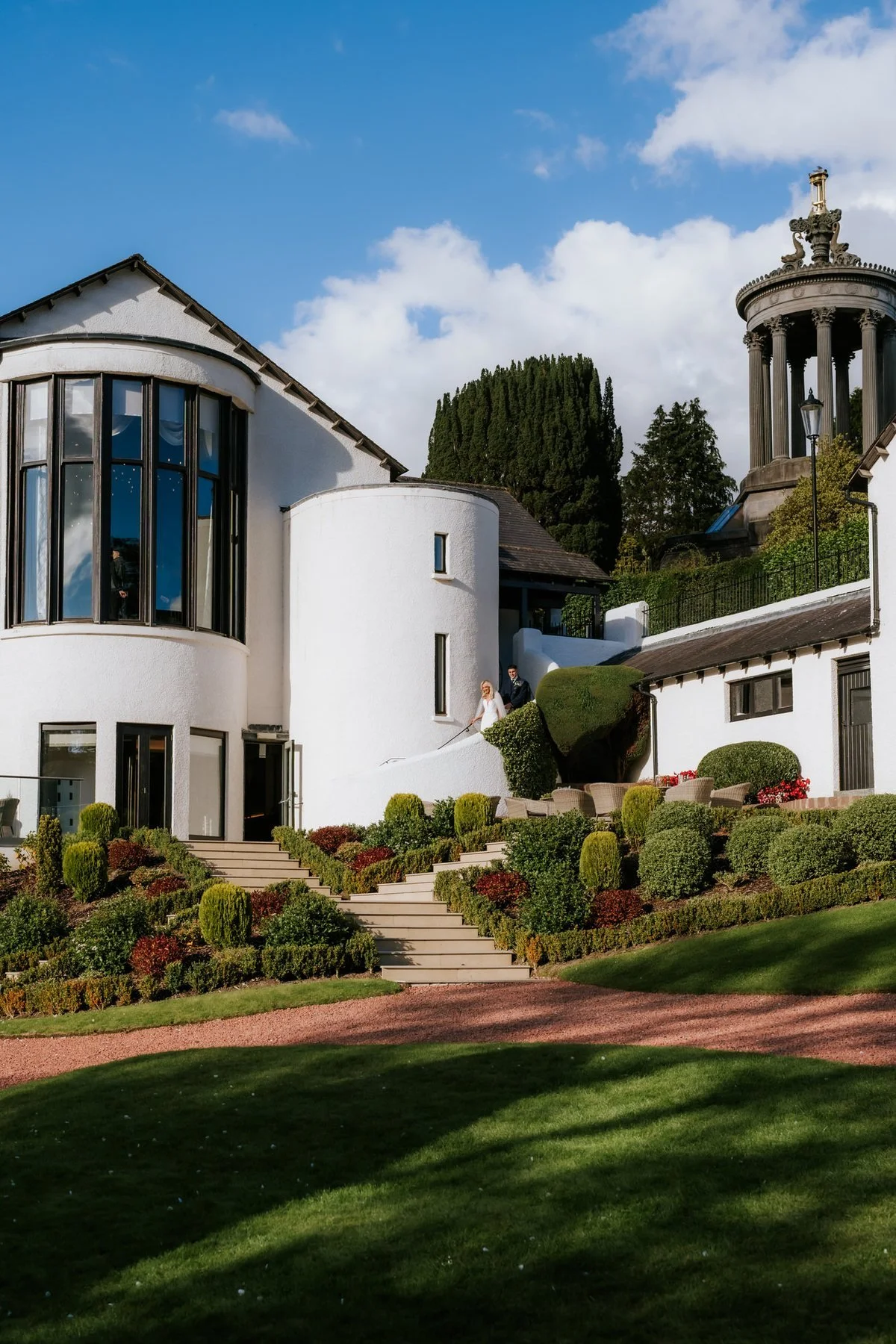 The white exterior of Brig o’ Doon House Hotel and its landscaped gardens in the sunshine.