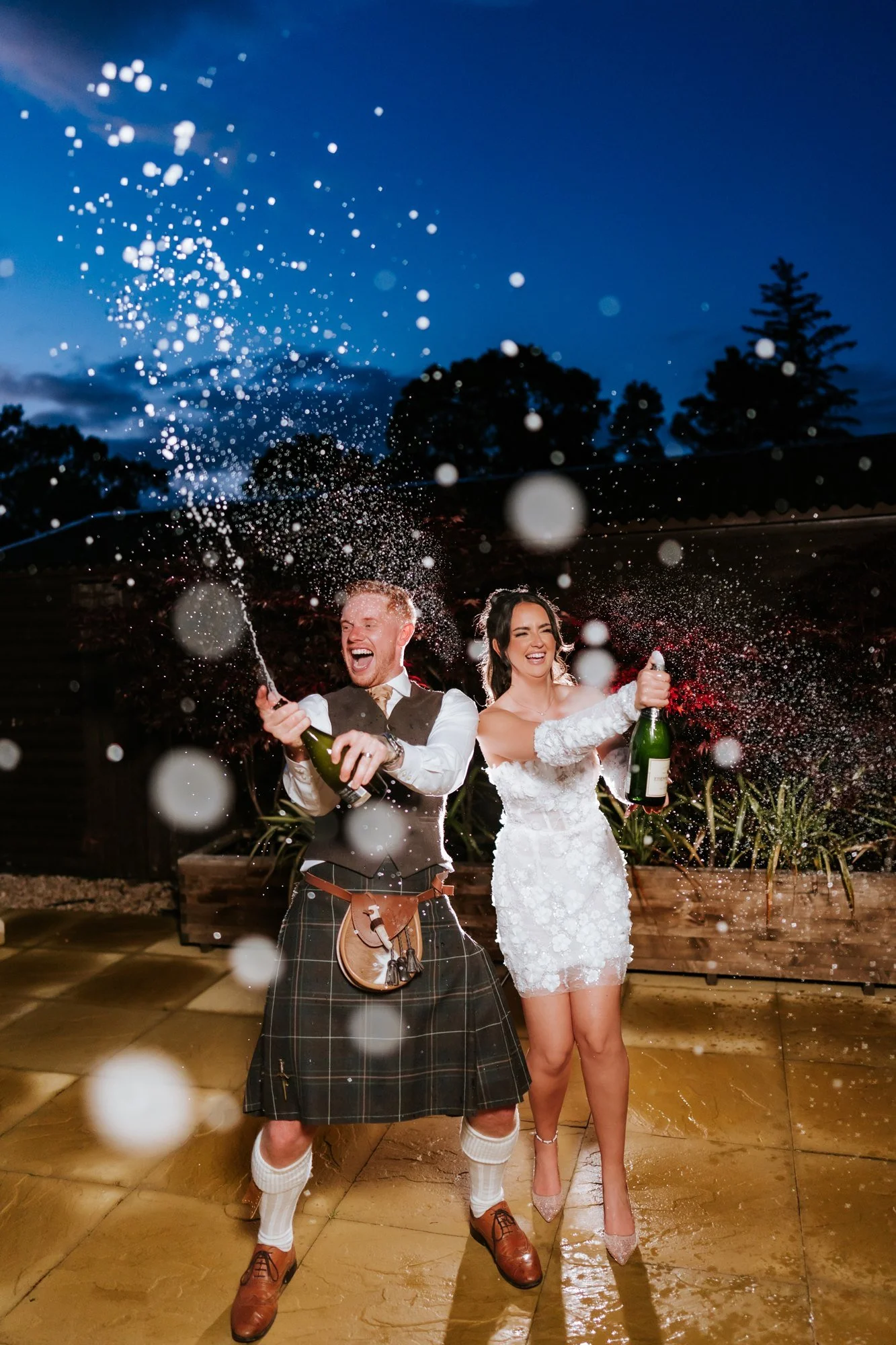 Champagne spraying through the air as Kaitlyn and Scott celebrate outside at Glenbervie House.