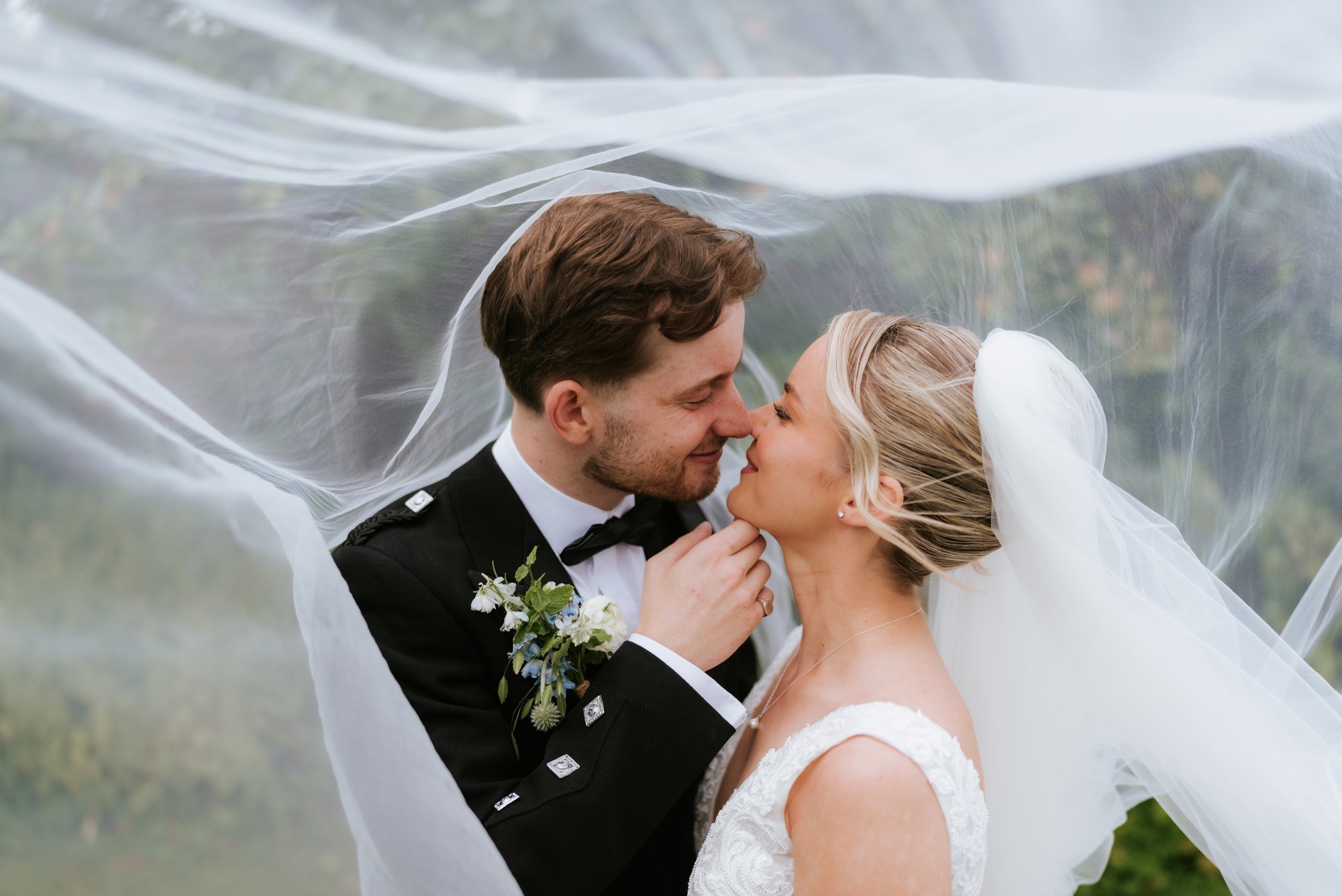 Lilian and Luke sharing a kiss beneath her veil.