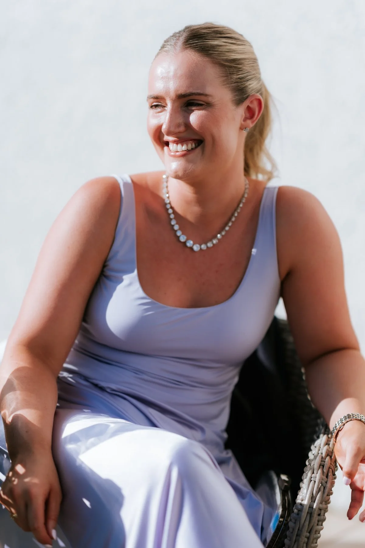 A guest in a pale blue outfit smiling outside in the sunshine.