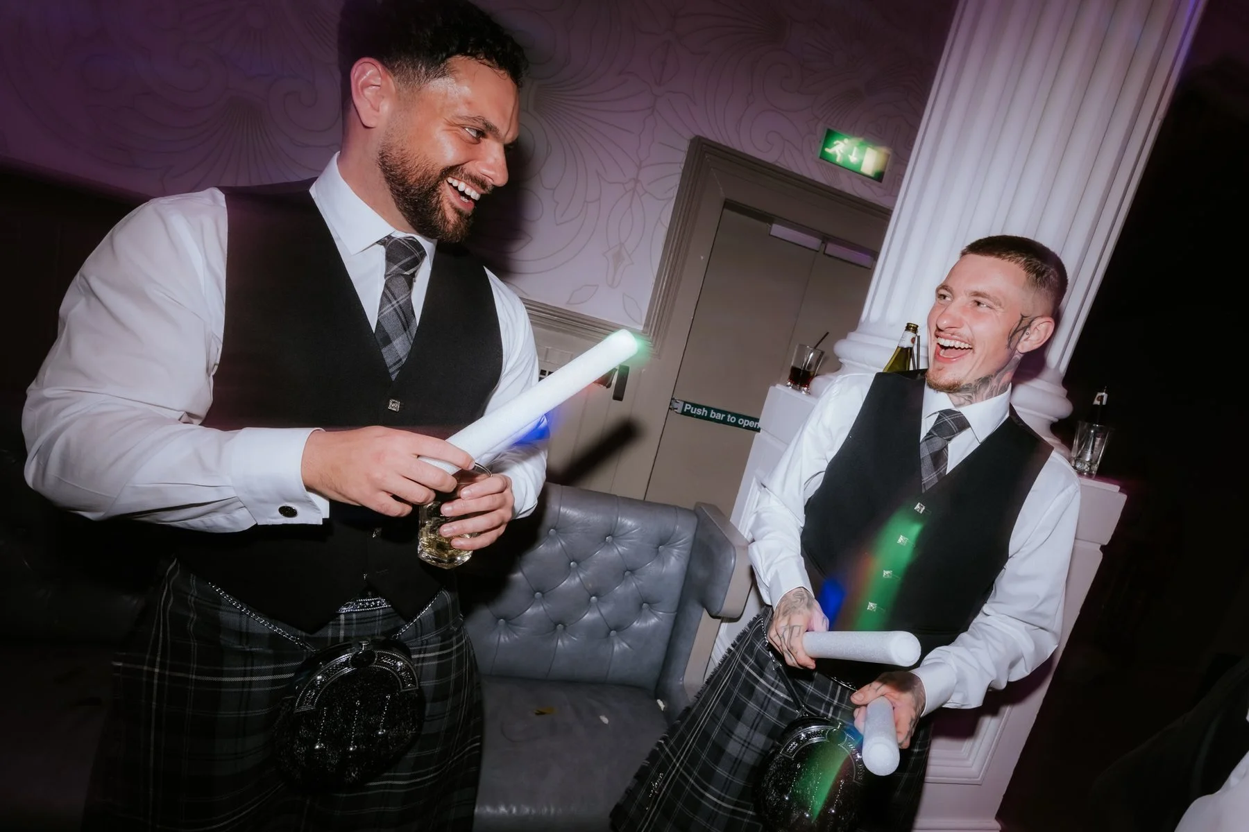 Two guests laughing together with light-up sticks during the evening party.