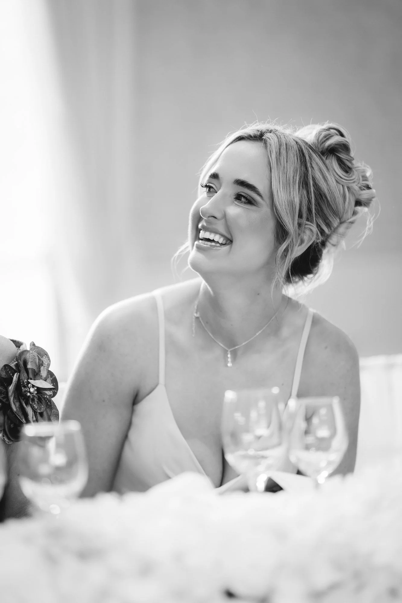 Black-and-white portrait of a bridesmaid smiling at the top table at Glenbervie House.