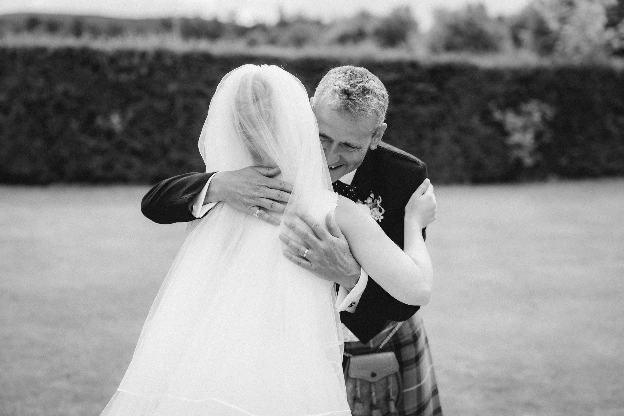 Black-and-white photograph of Lilian hugging her dad in the garden before the ceremony.