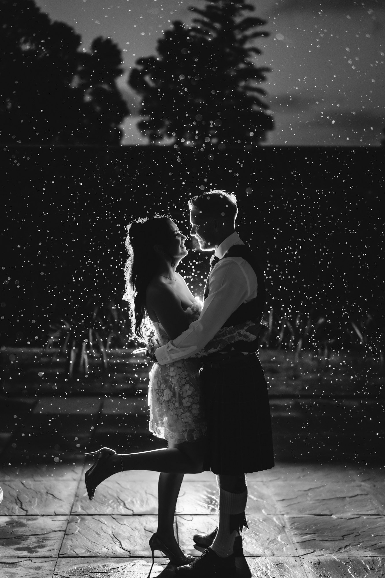 Black-and-white portrait of Kaitlyn and Scott embracing in sparkling rain at Glenbervie House.