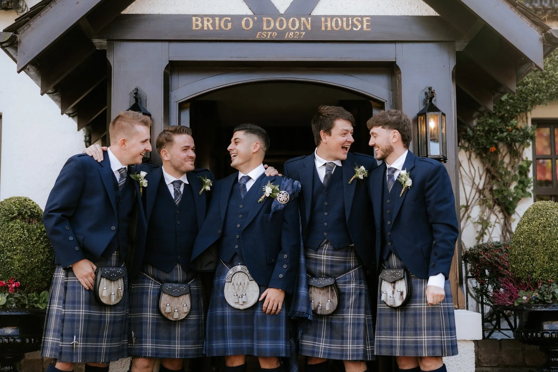 Zen and his groomsmen laughing together outside the entrance to Brig o’ Doon House Hotel.