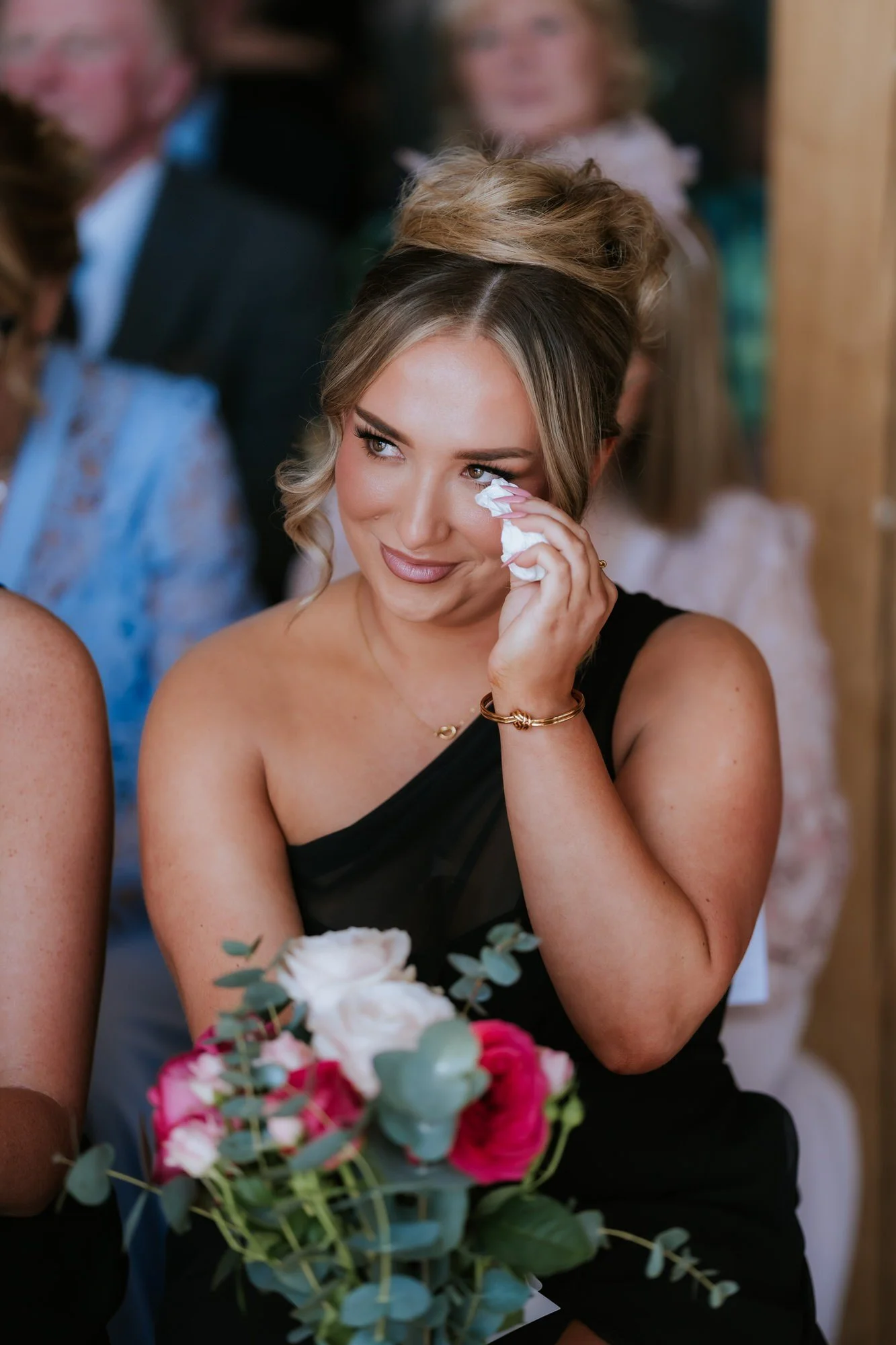 A bridesmaid holding a tissue as she watches the ceremony.