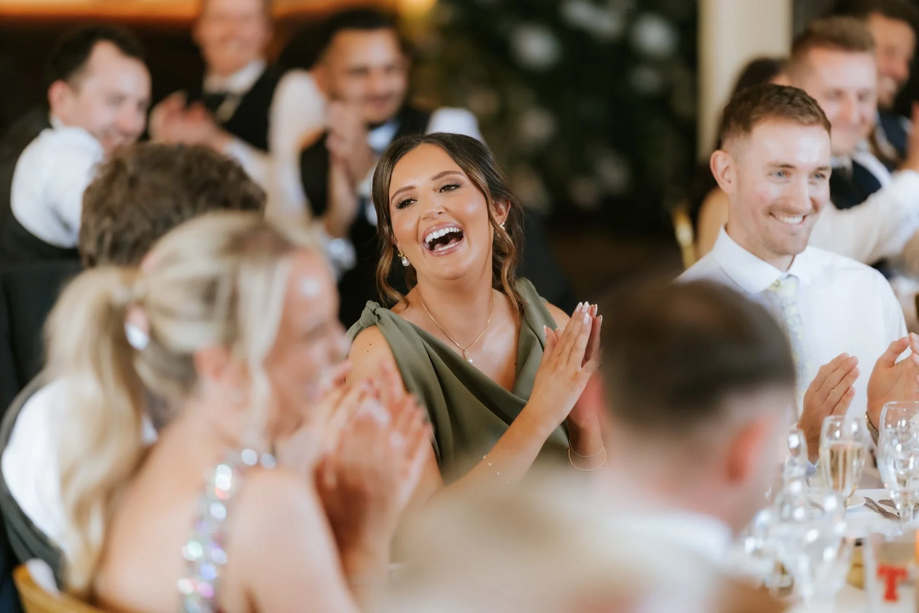 A bridesmaid laughing with guests around the wedding breakfast table.