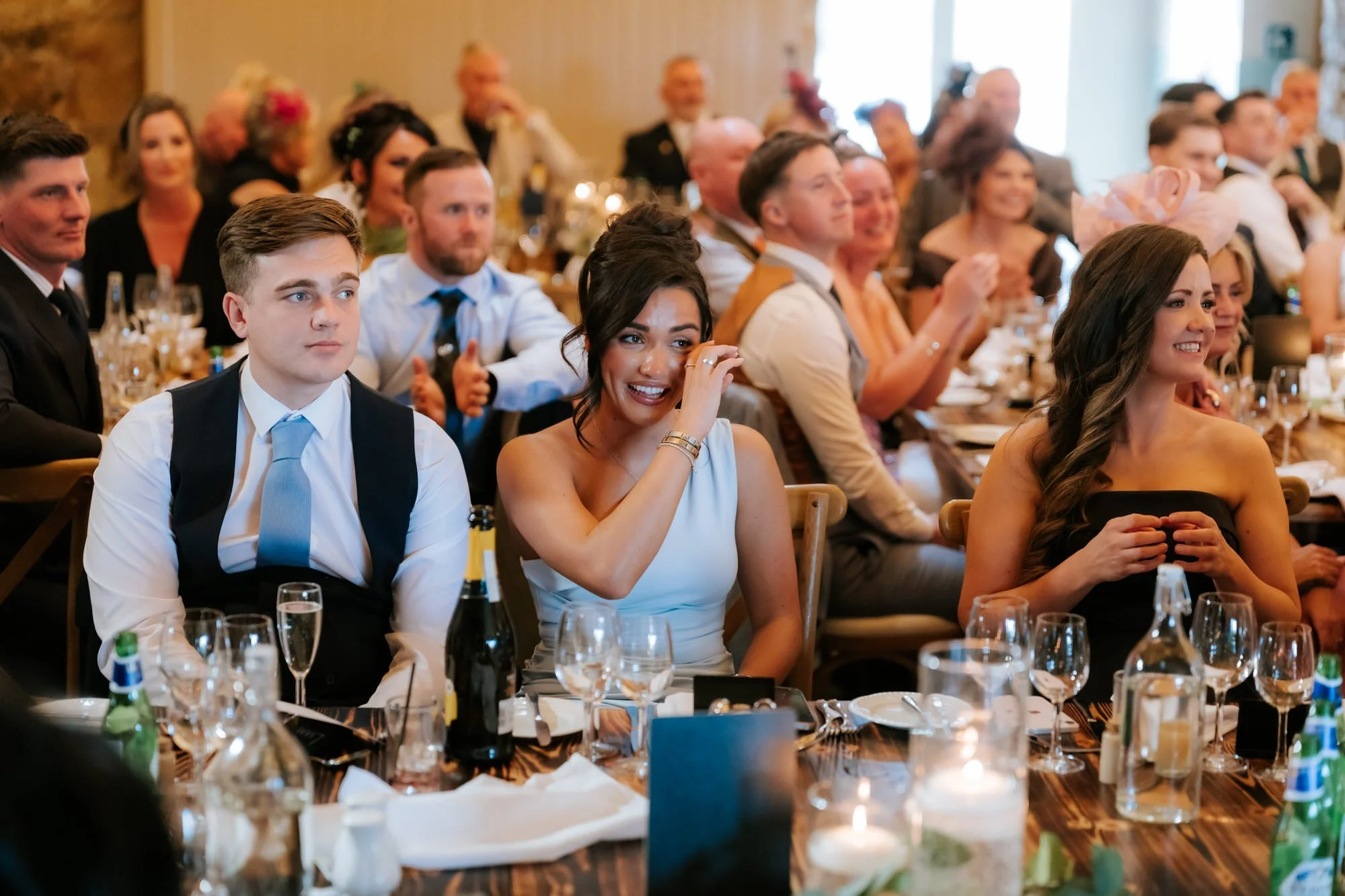 Wedding guests laughing and reacting at their reception table