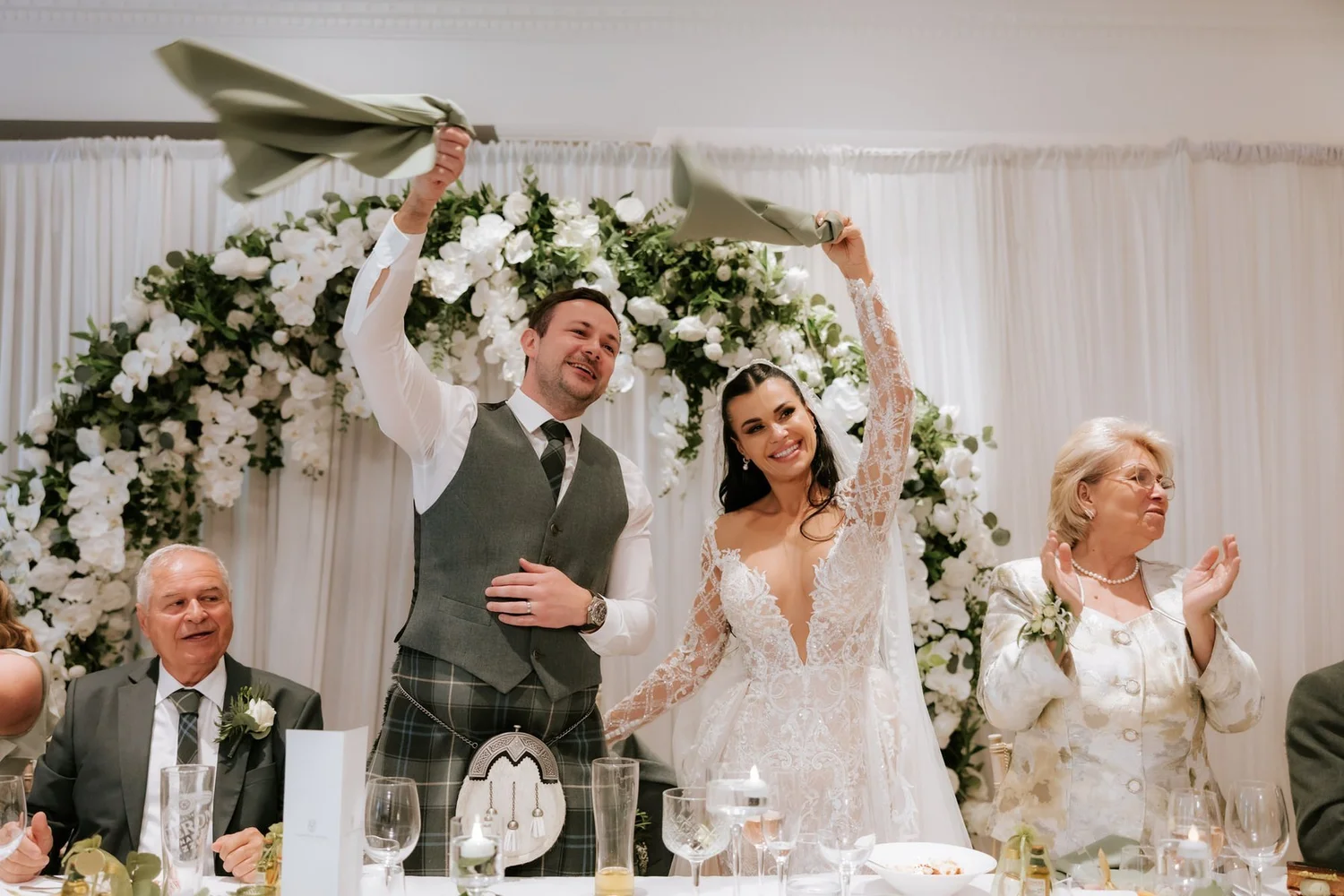 Cristina and Connor waving napkins above their heads at their wedding reception.