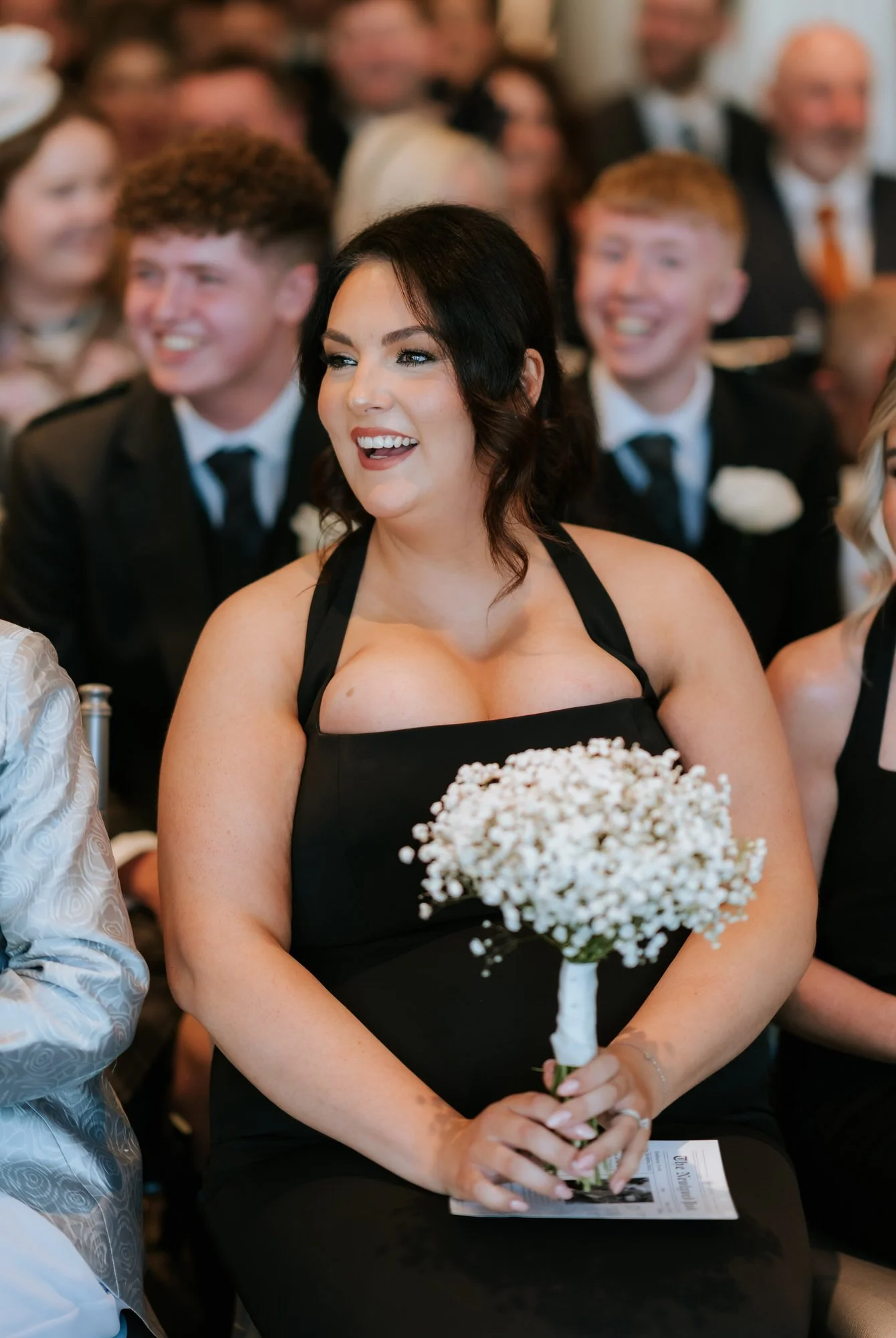 A brunette bridesmaid smiling as she watches the ceremony