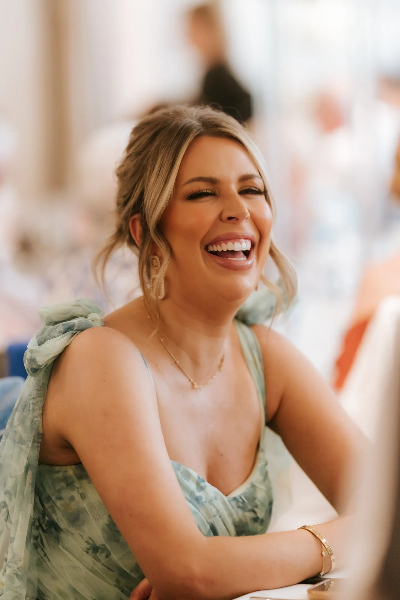 A guest in green laughing during the wedding reception