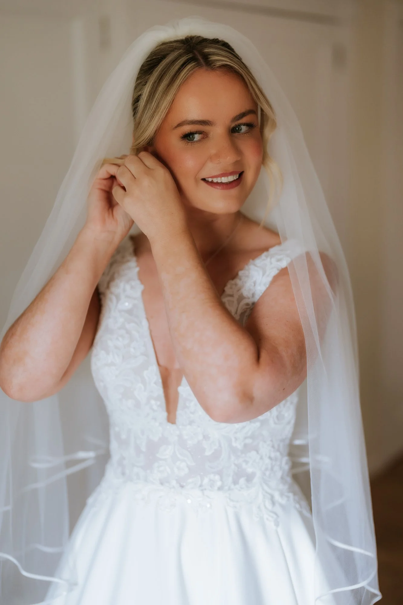 Lilian putting on her earrings with her veil in place.