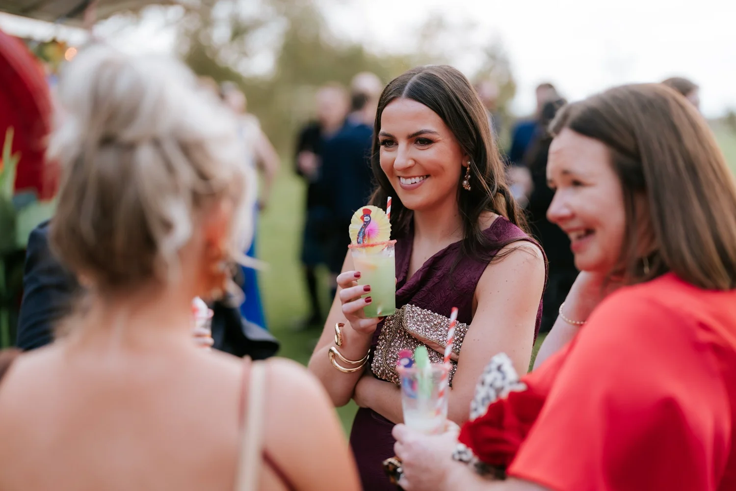 Guests chat over drinks in the courtyard, including a woman holding a colourful cocktail.