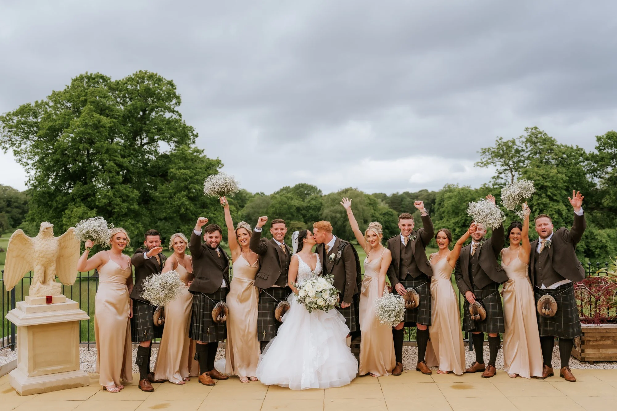 Kaitlyn and Scott kissing as their wedding party cheers on the terrace at Glenbervie House.