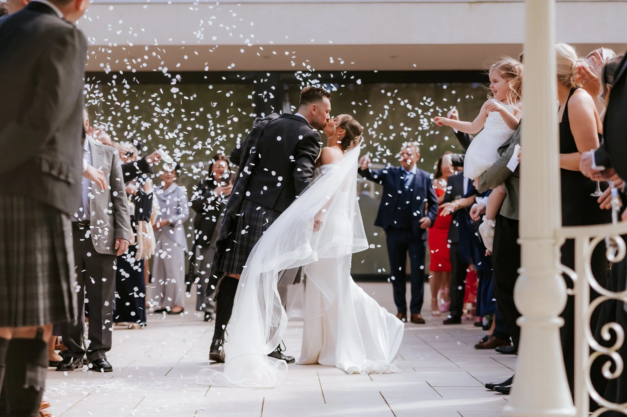 Elle and Adam kissing beneath falling confetti
