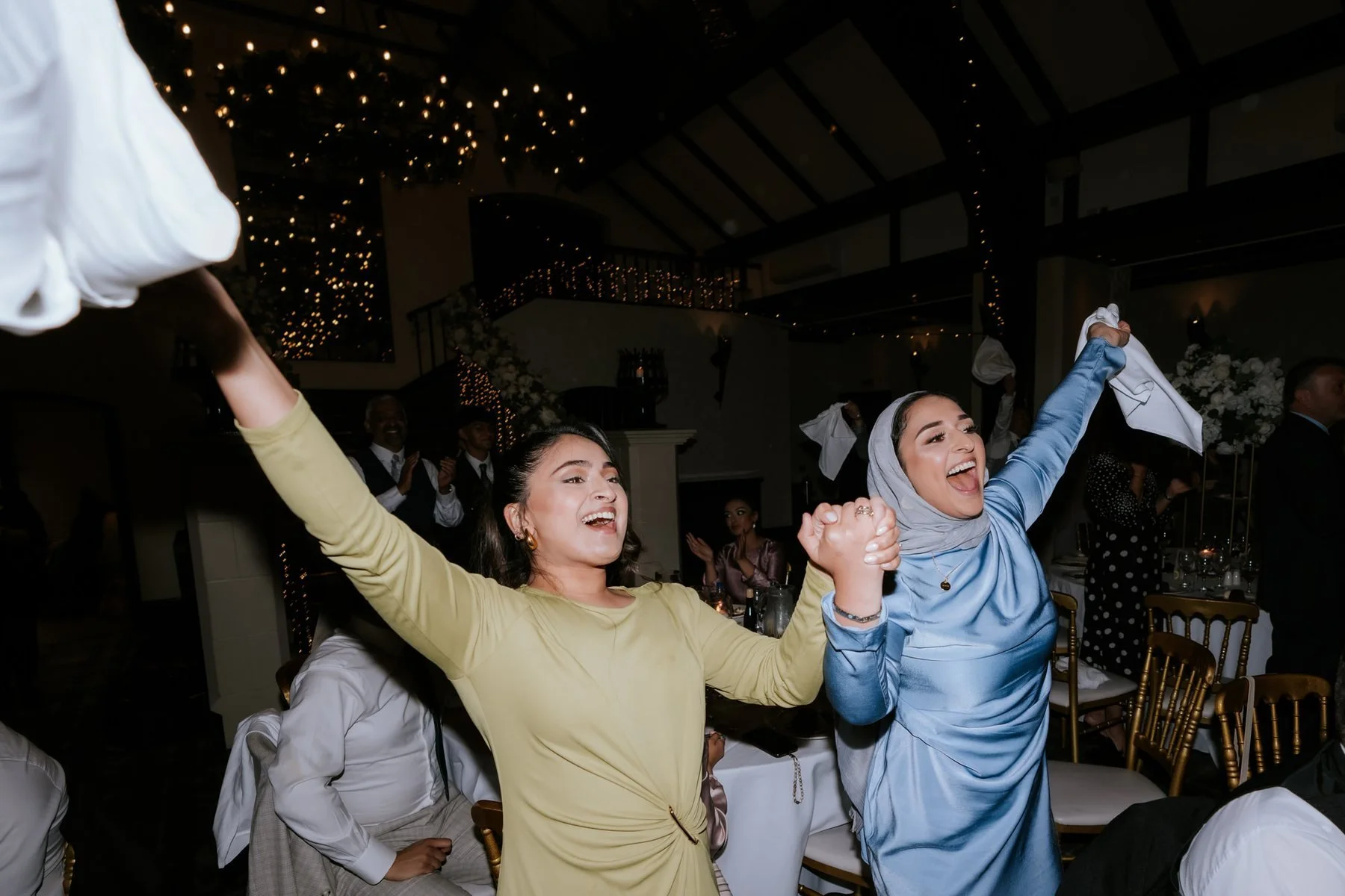 Two guests laughing with their arms raised during the evening celebrations.