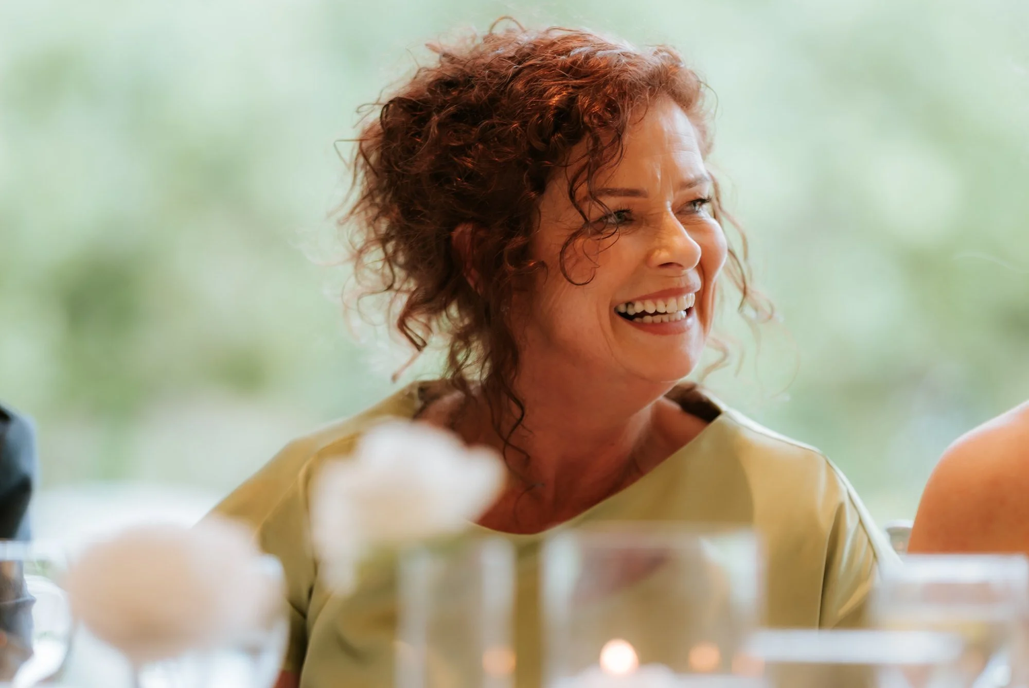 A guest in a lime dress smiling across the reception table