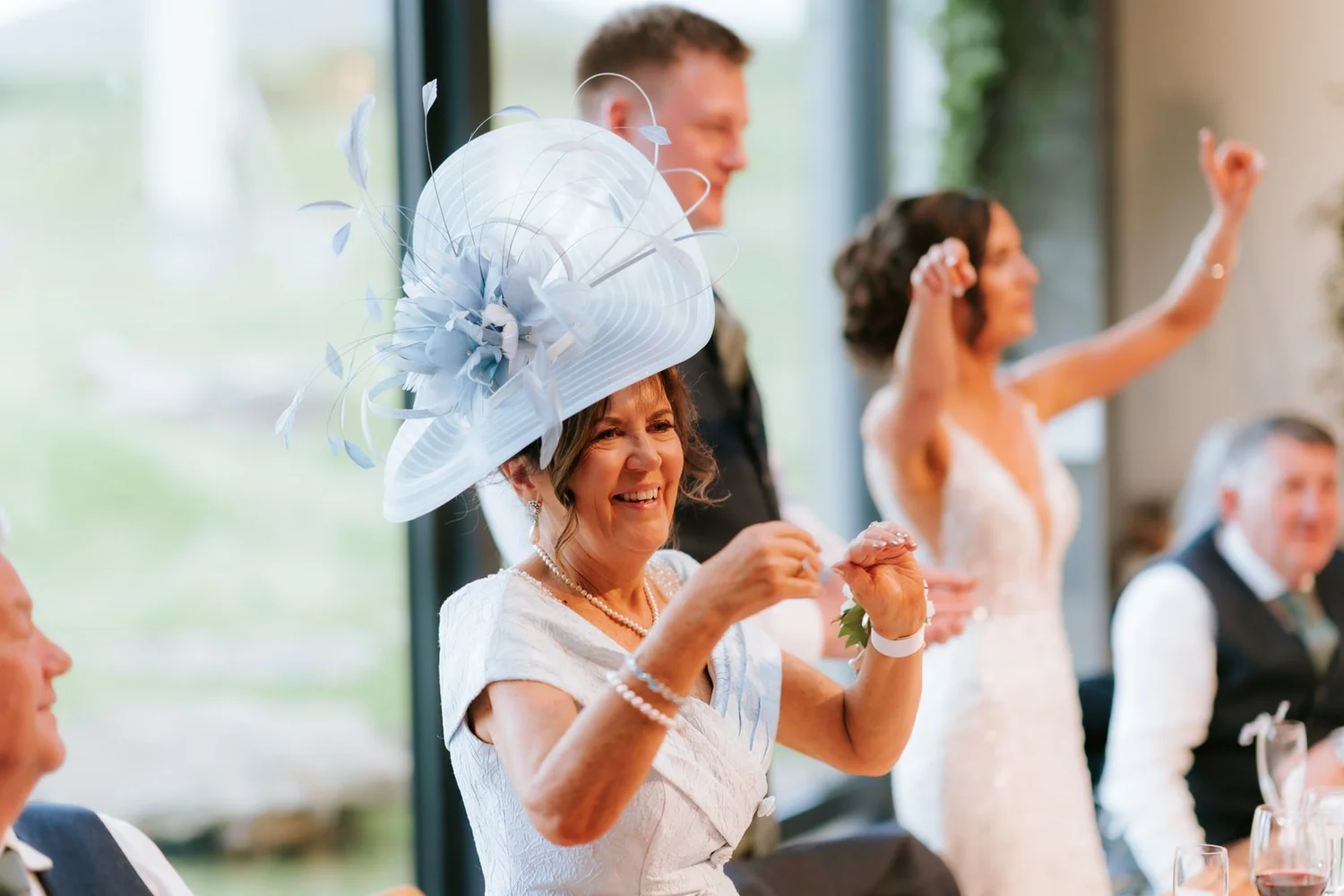 A guest in a blue hat clapping while Lauren cheers behind her.