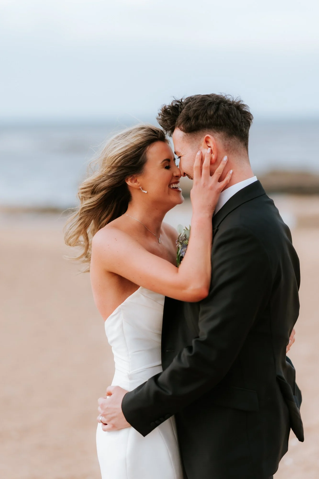 Natalie and Jamie laughing together during their beach portraits