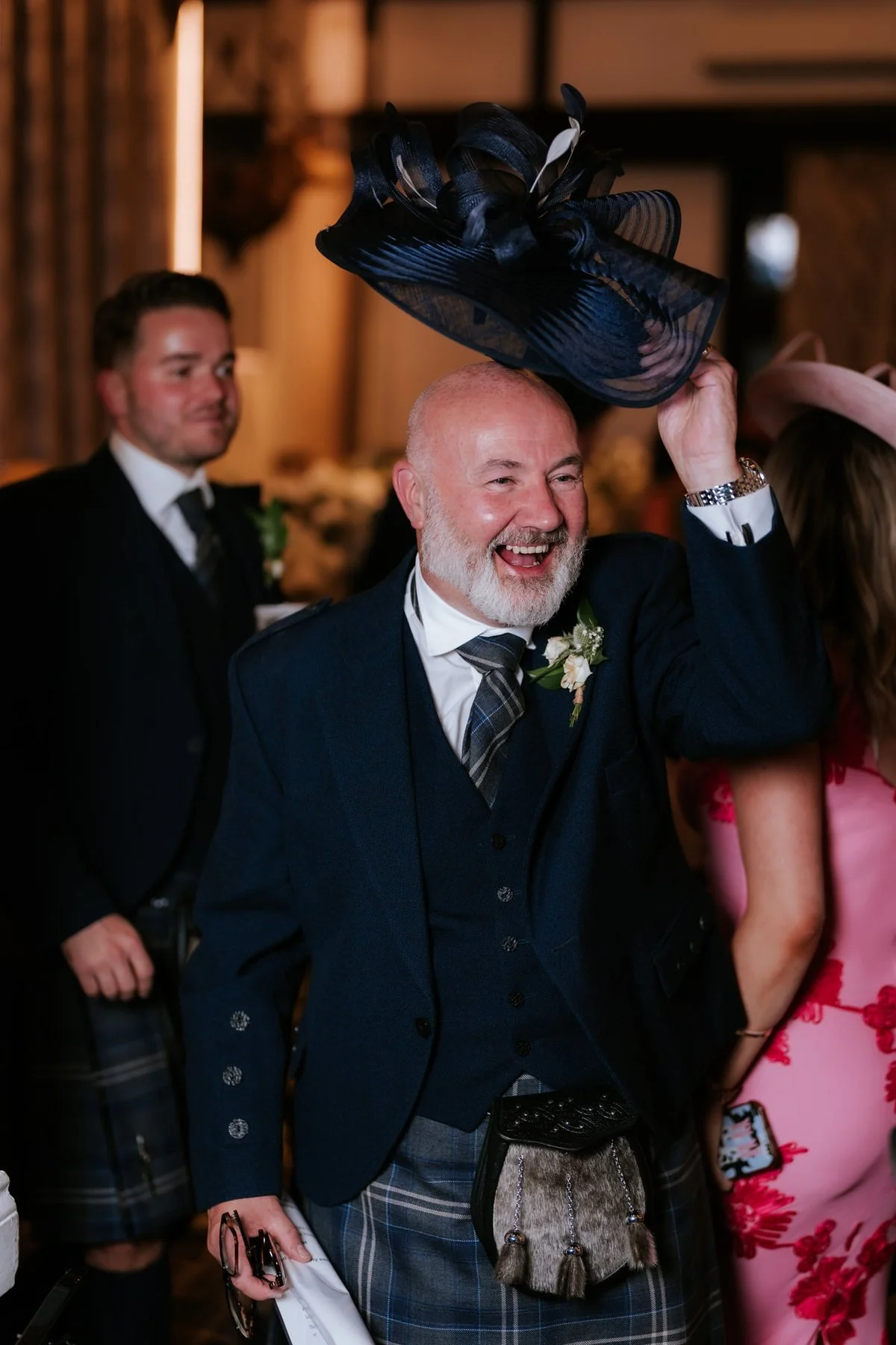 A guest in a navy kilt outfit singing and celebrating at the reception.
