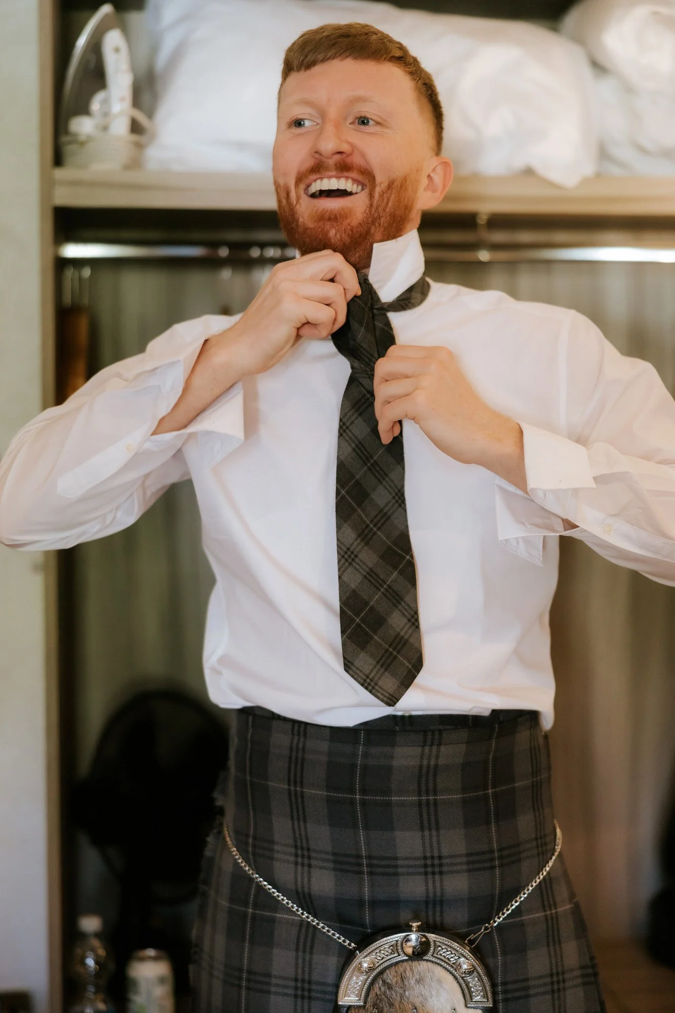 A groomsman laughing while getting ready