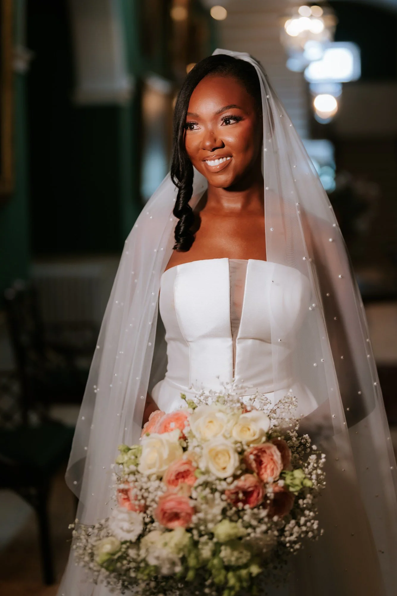 Kuda holding her bouquet in the green picture-lined corridor.