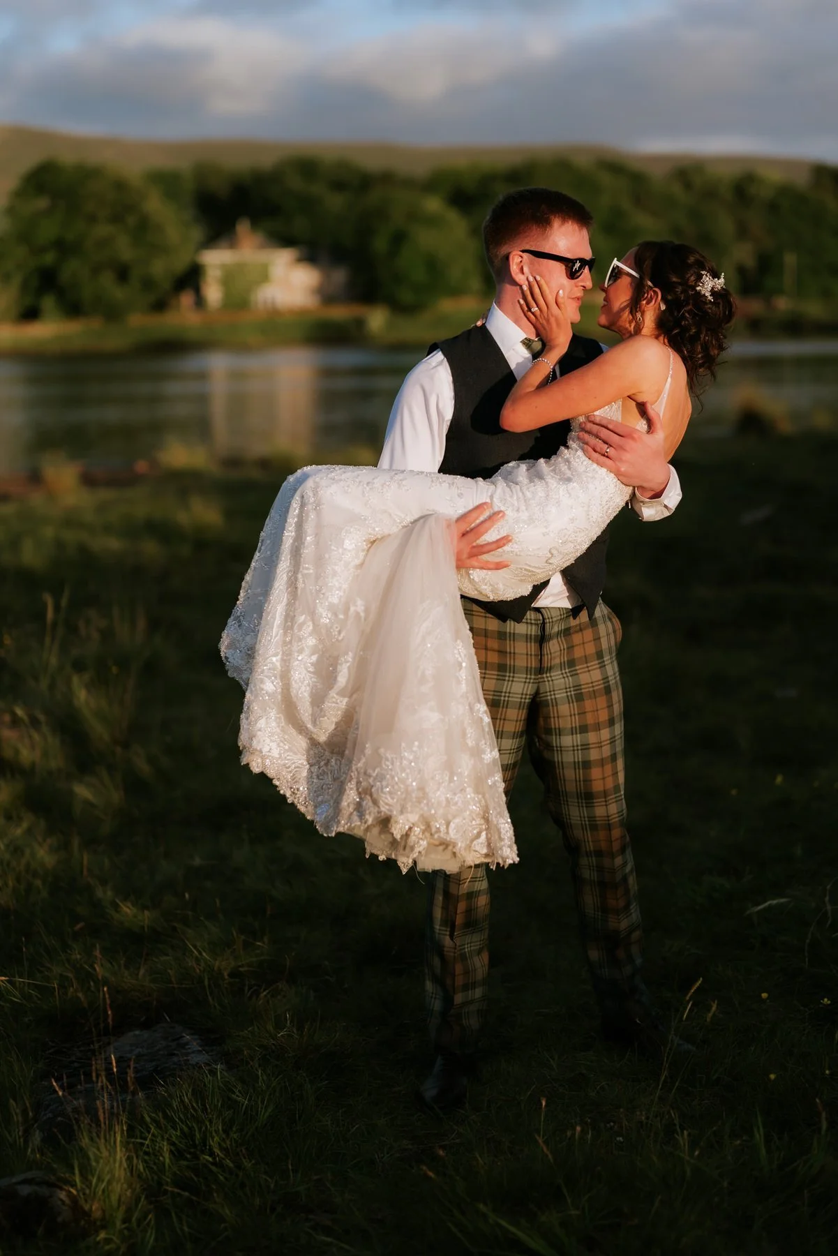 Jamie carrying Lauren in his arms beside the water at Cairns Farm.