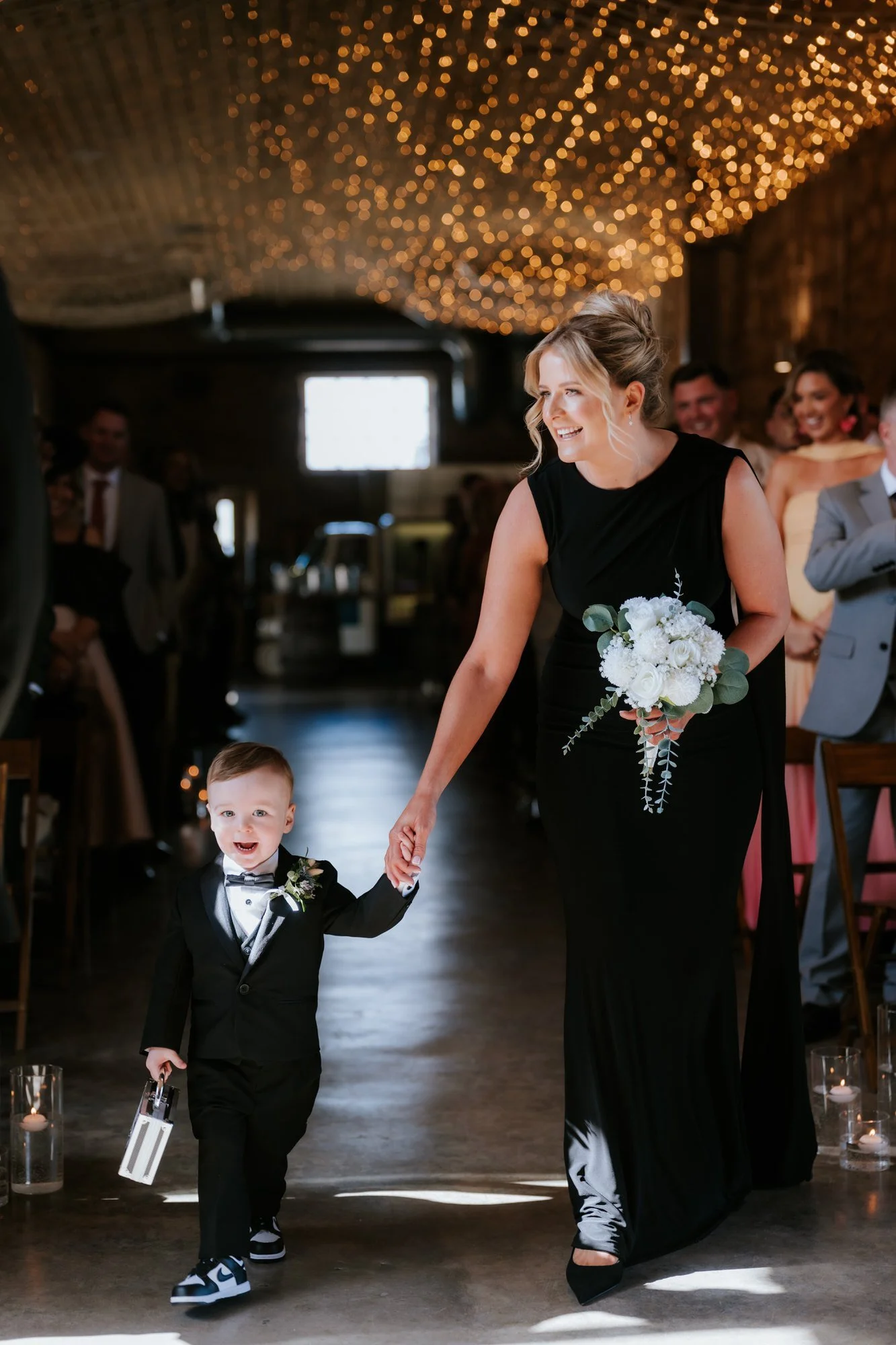 A bridesmaid walking down the aisle with a young ring bearer