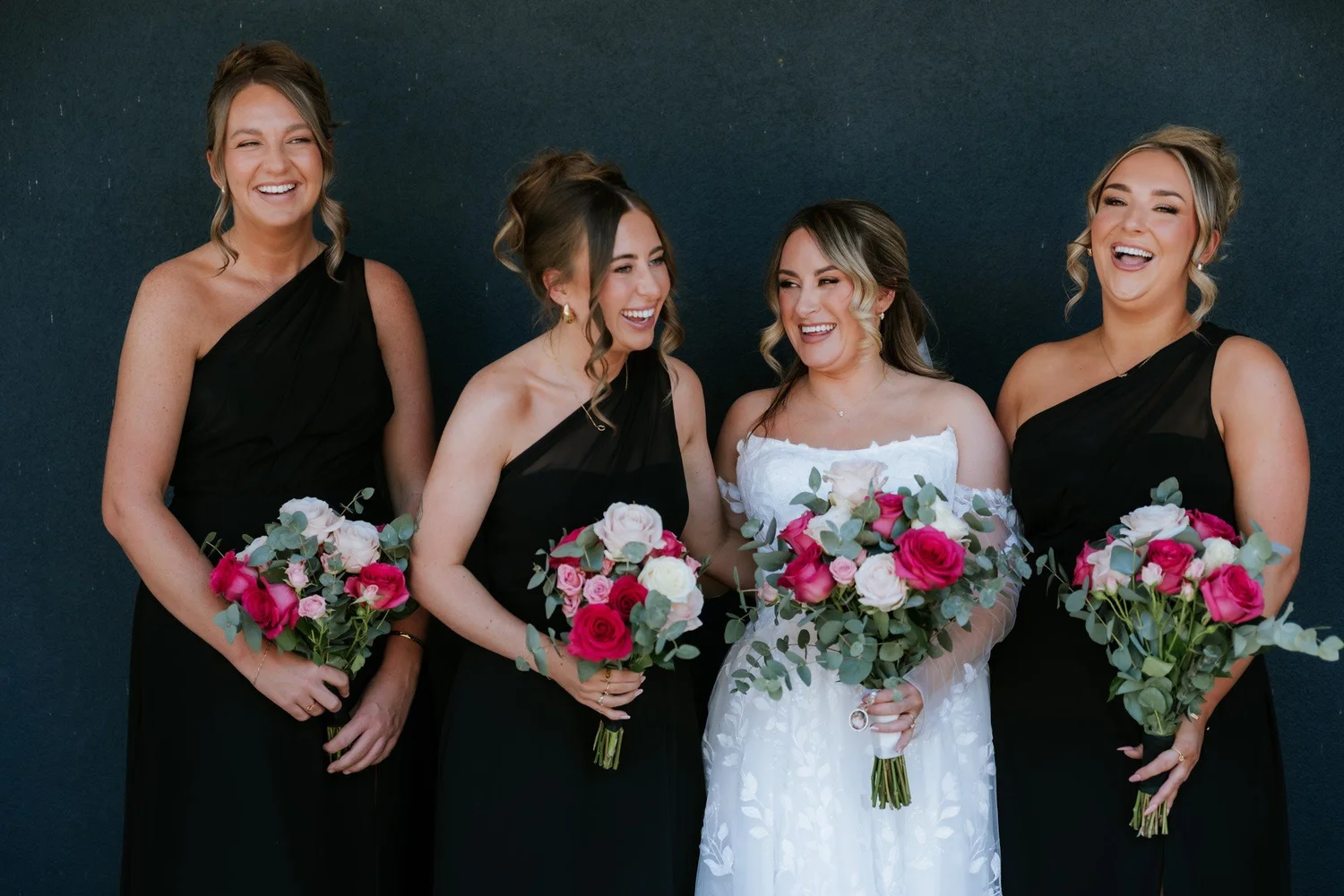 Ciara and her bridesmaids laughing together with their bouquets.
