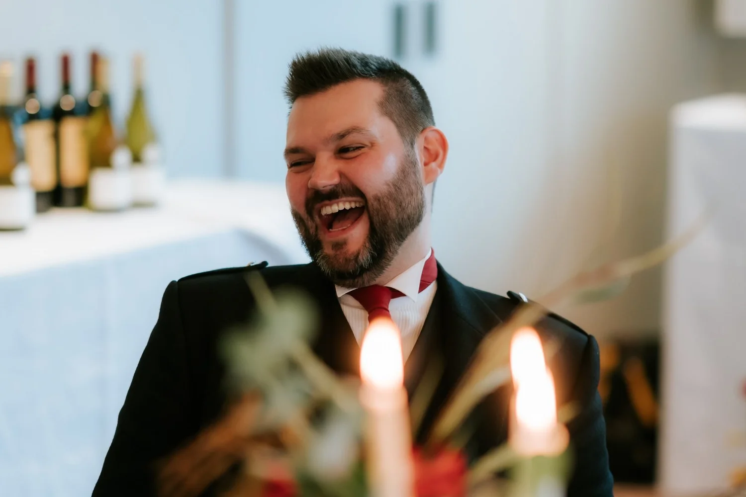 A guest in a red bow tie laughing during the wedding speeches.