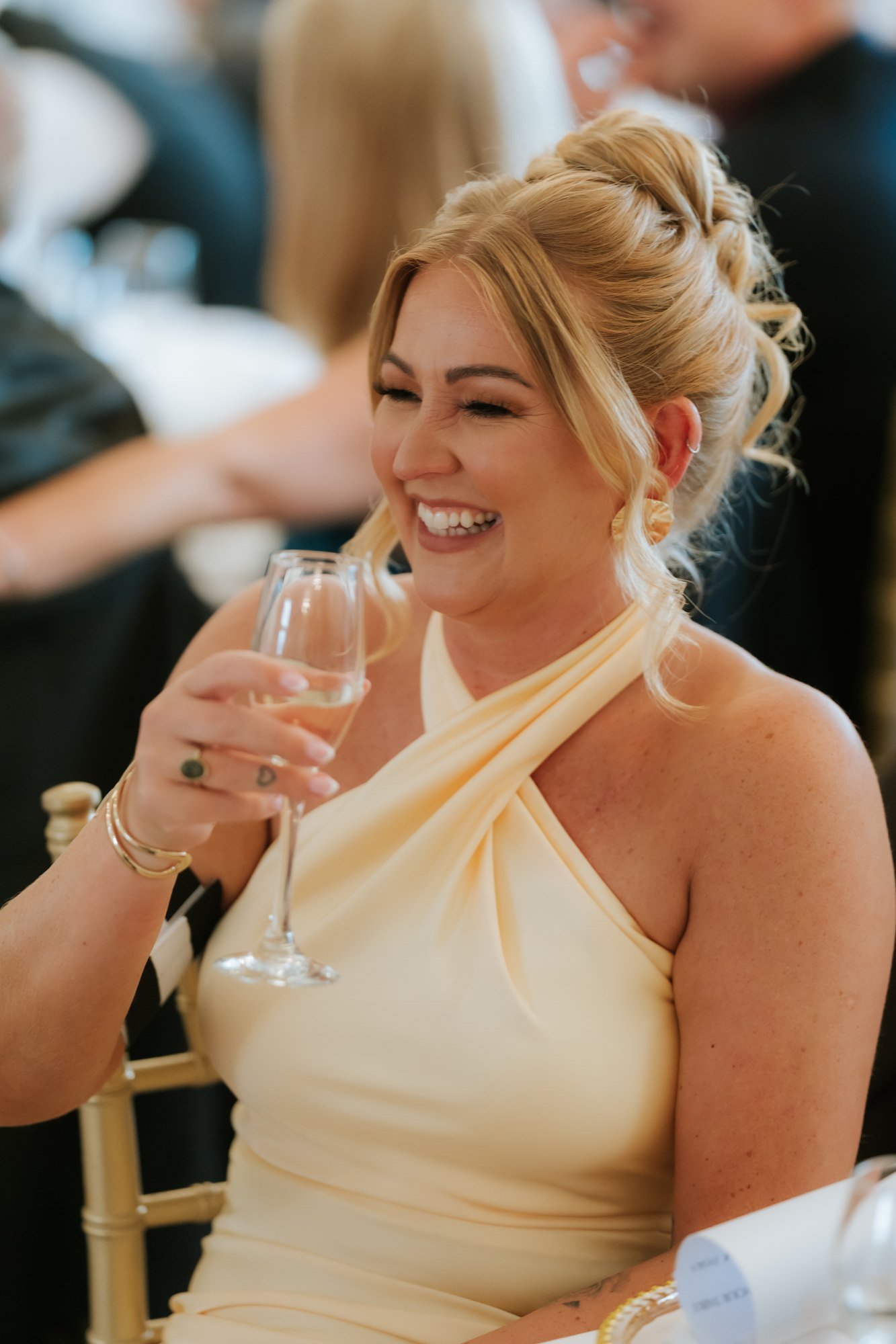 A smiling wedding guest holding a champagne flute at Glenbervie House.