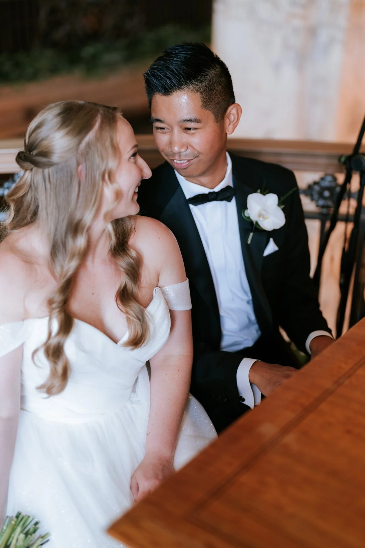Allie and Carl smiling at each other while seated together at their wedding.