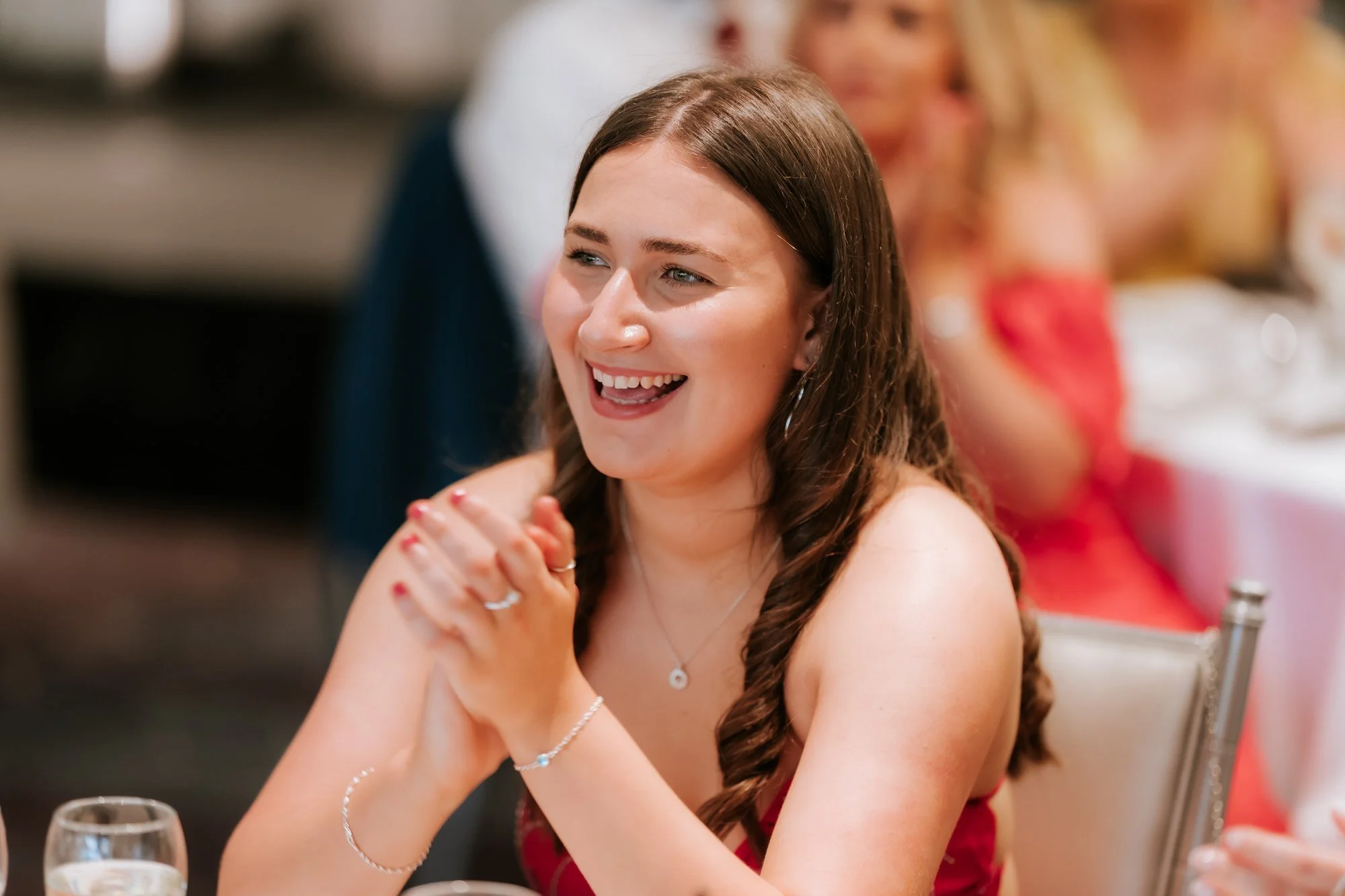 A guest in a red dress clapping and smiling