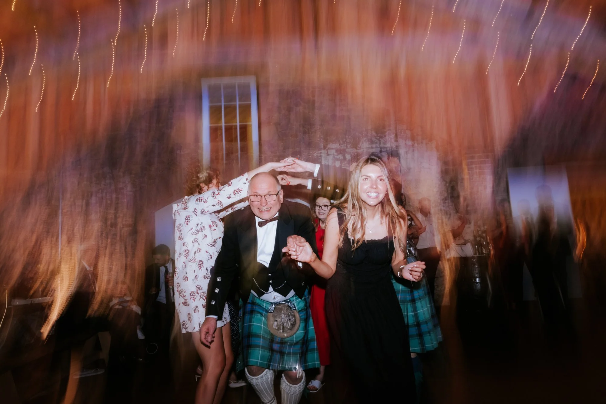 Wedding guests celebrating on the dance floor beneath the evening lights.