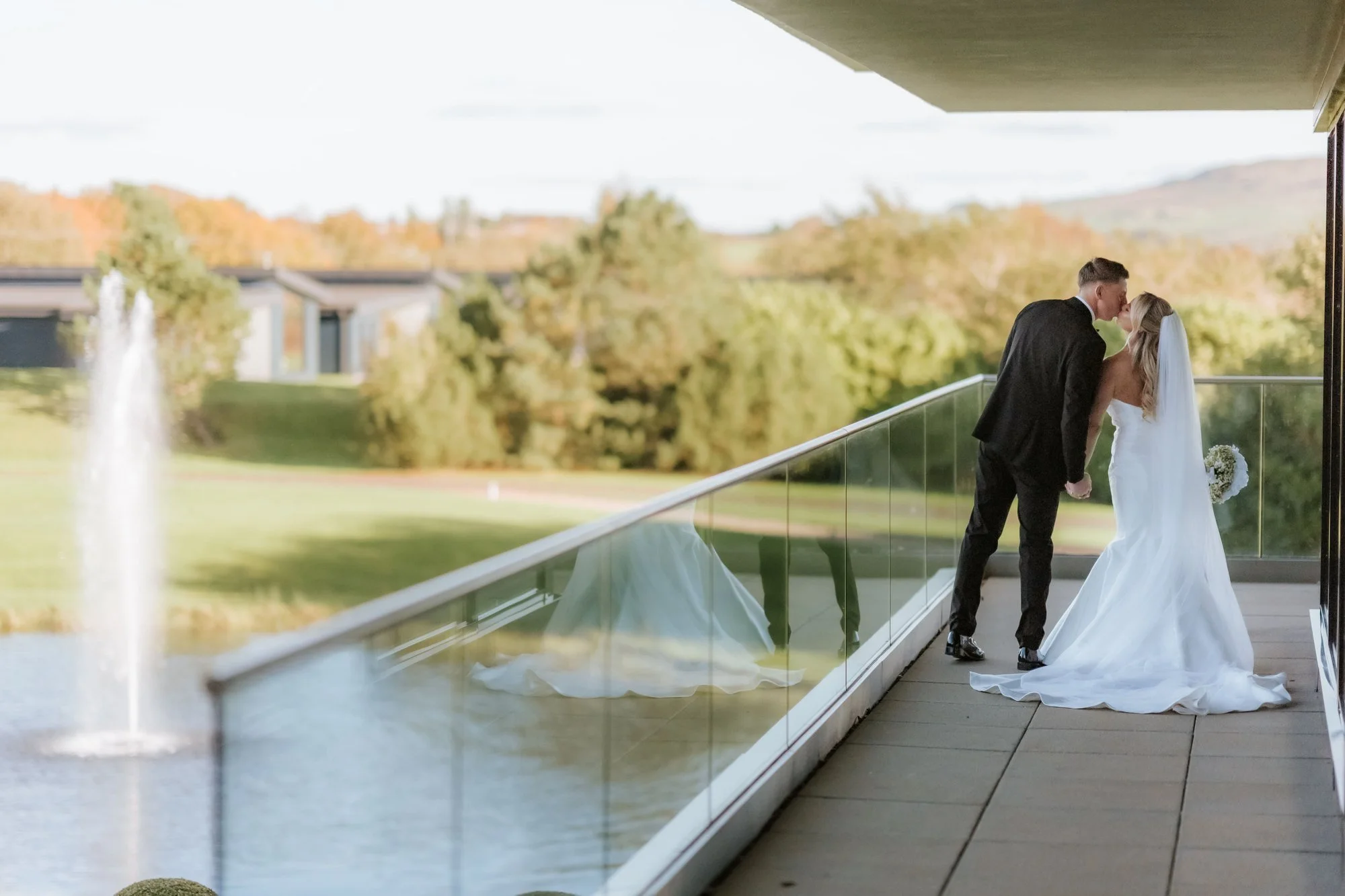 Aiden and Taylor sharing a kiss on the balcony overlooking the gardens.