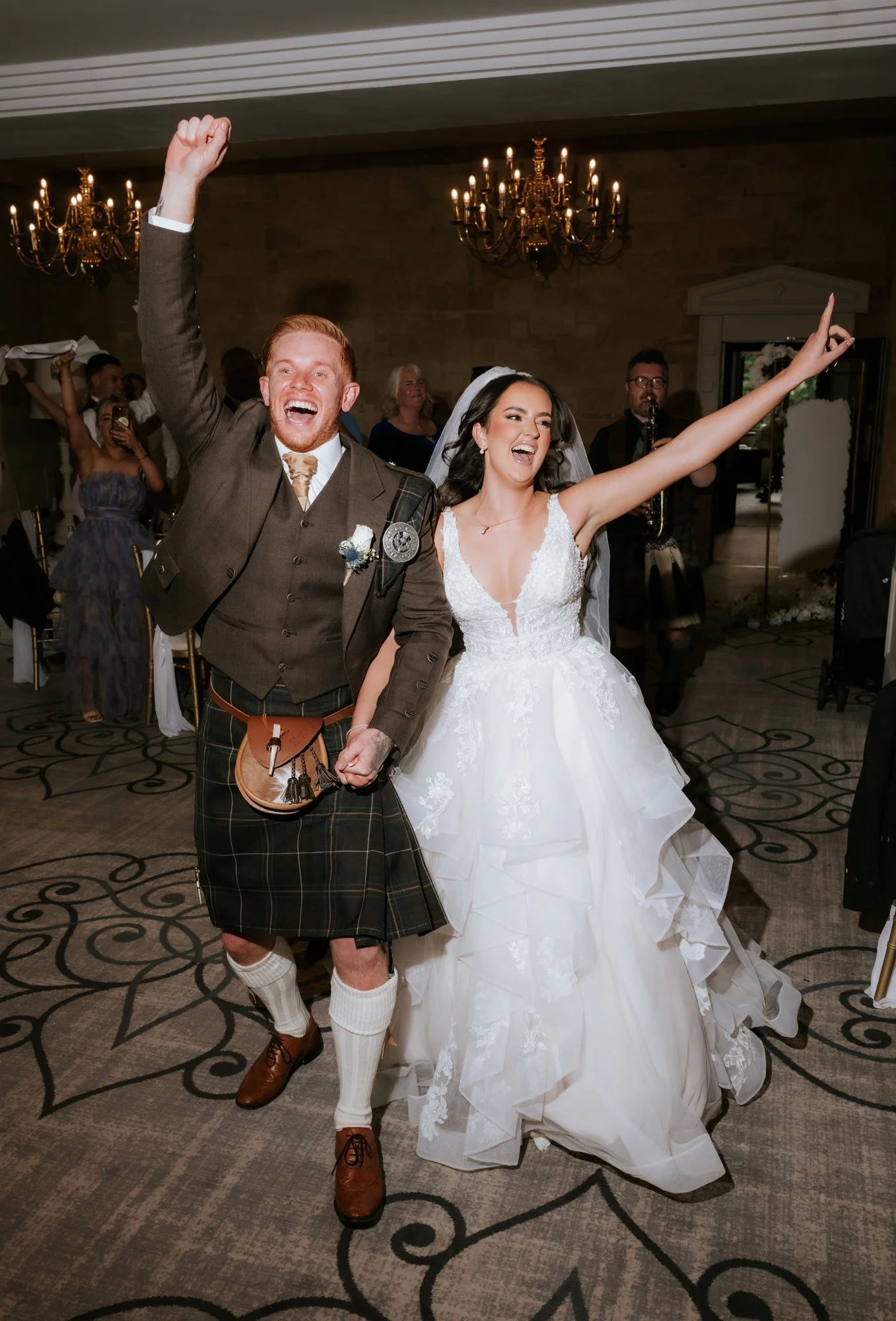 Kaitlyn and Scott entering their wedding reception with their arms raised at Glenbervie House.