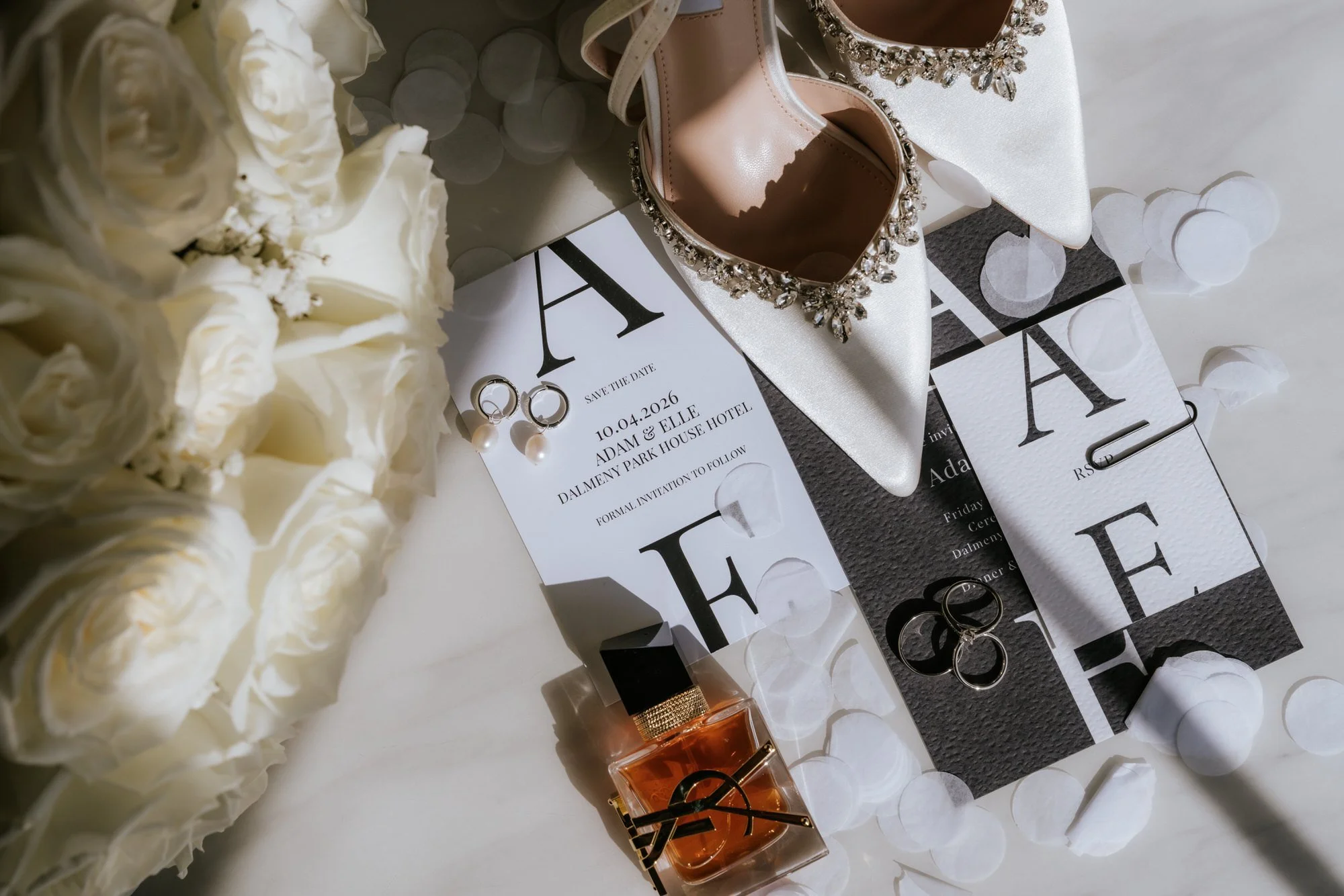 Elle and Adam's wedding stationery with white shoes, flowers and jewellery