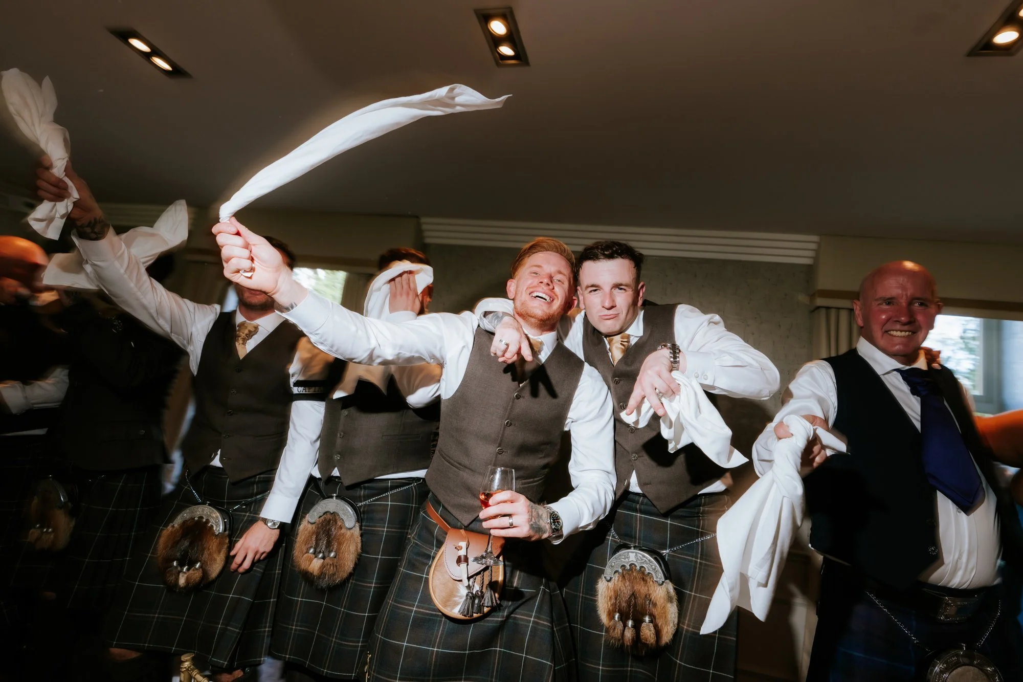 Scott and his friends waving napkins and celebrating together at Glenbervie House.