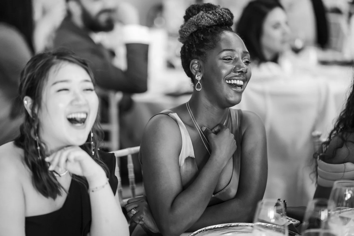 Two bridesmaids laughing during the wedding reception, photographed in black and white.