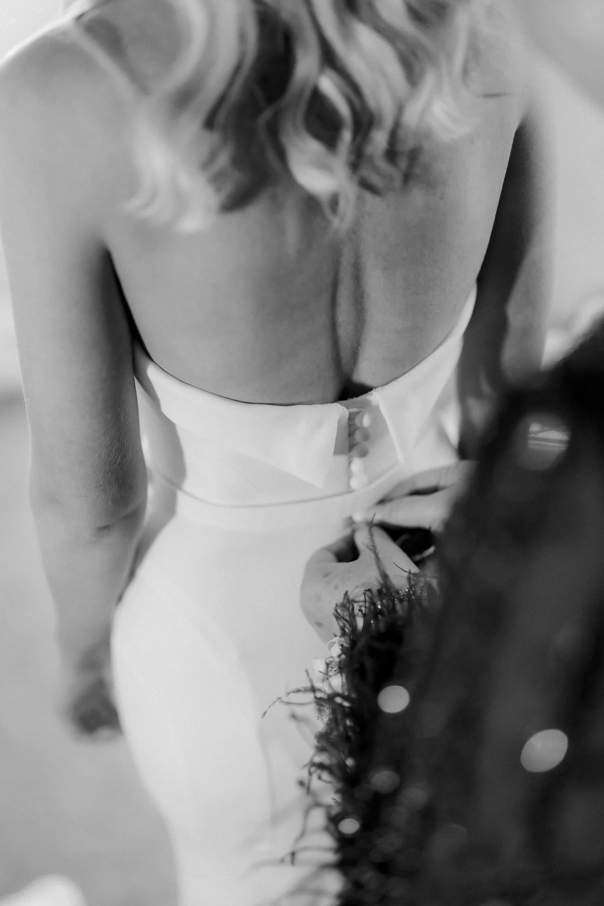 The buttons on the back of Lauren’s wedding dress being fastened.