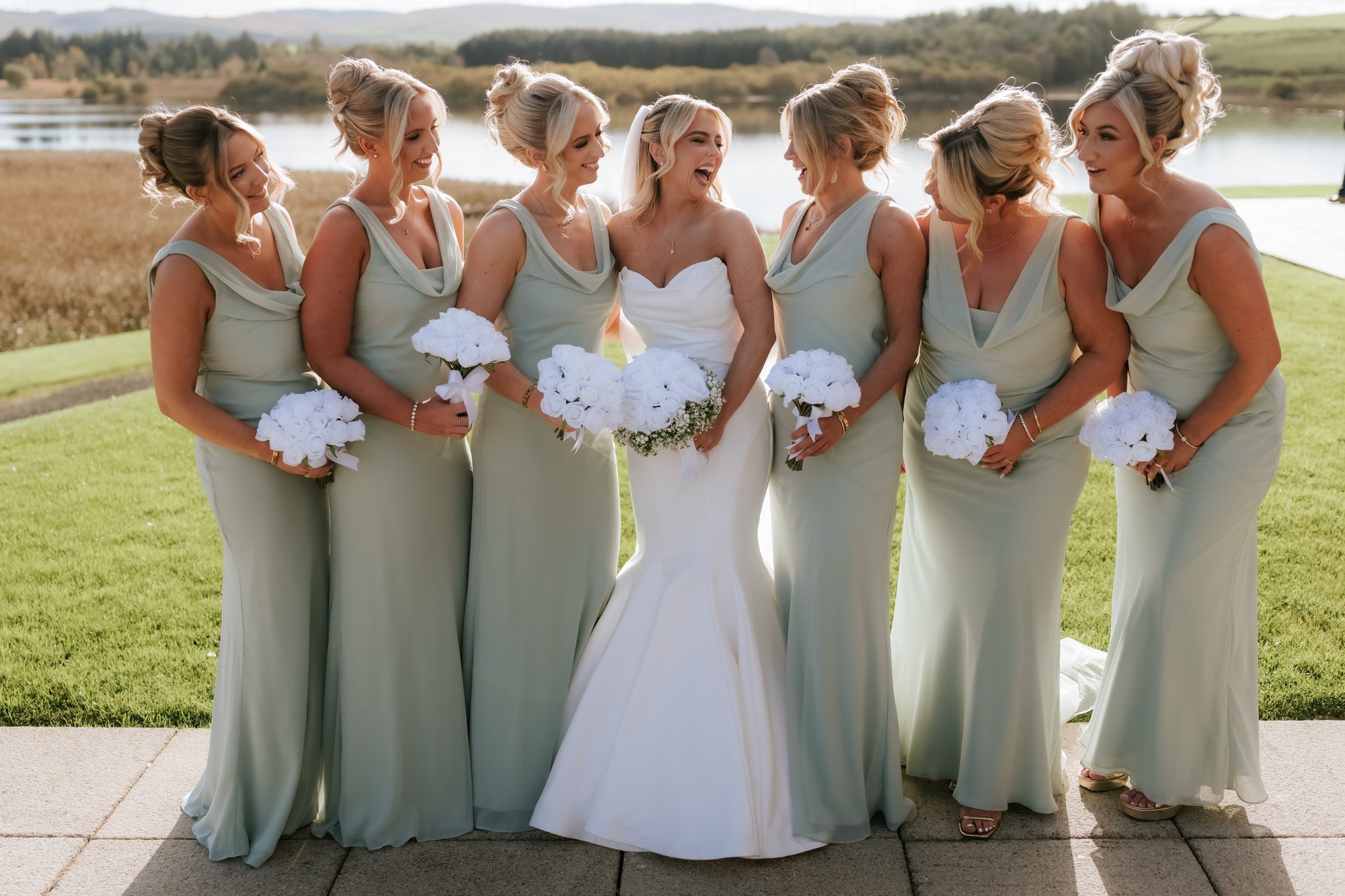 Taylor laughing with her bridesmaids beside the loch.